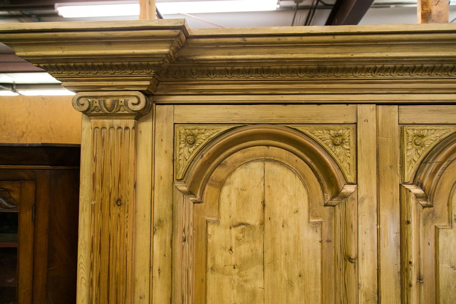 Ce meuble de divertissement en pin a été fabriqué à partir de pin ancien récupéré. Les portes supérieures sont dotées de panneaux arqués en relief encadrés par de lourdes moulures et des panneaux d'angle sculptés. Les montants ont des pilastres