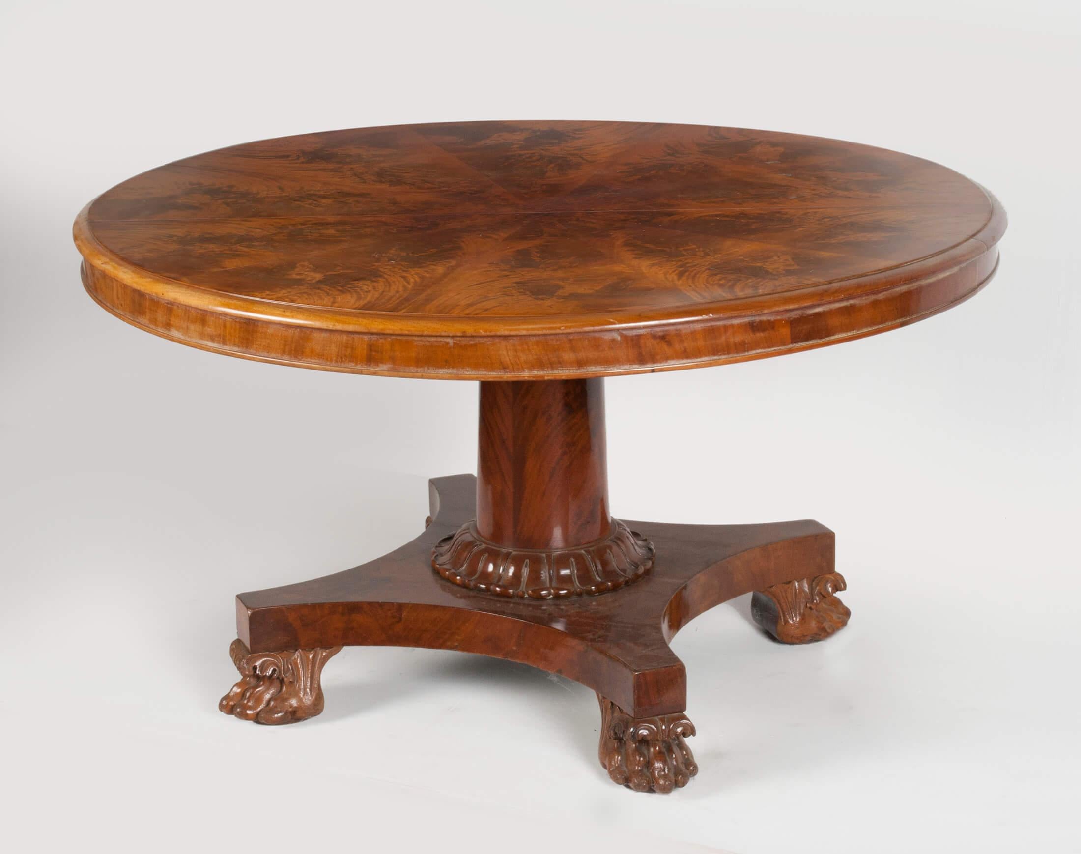 Antique burl mahogany veneered dining table in Empire style. On a pedestal base with claw feet. This table is made in England in 1890-1900. The tabletop is bookmatched veneer. The table is original extensible, but it's without the extension panels.
