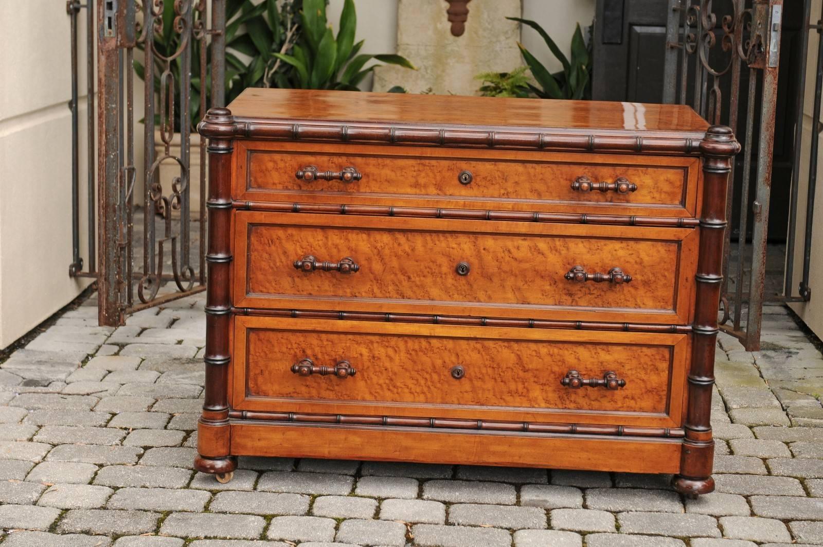 An English faux-bamboo and burled walnut veneered three-drawer commode from the late 19th century. This English chest features an exquisite burled walnut structure, accented by a faux-bamboo frame of darker tones. A rectangular top sits above three