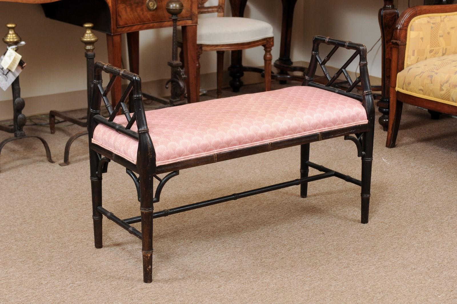 An English faux bamboo black painted window bench with arms, upholstered seat and stretcher below.
  