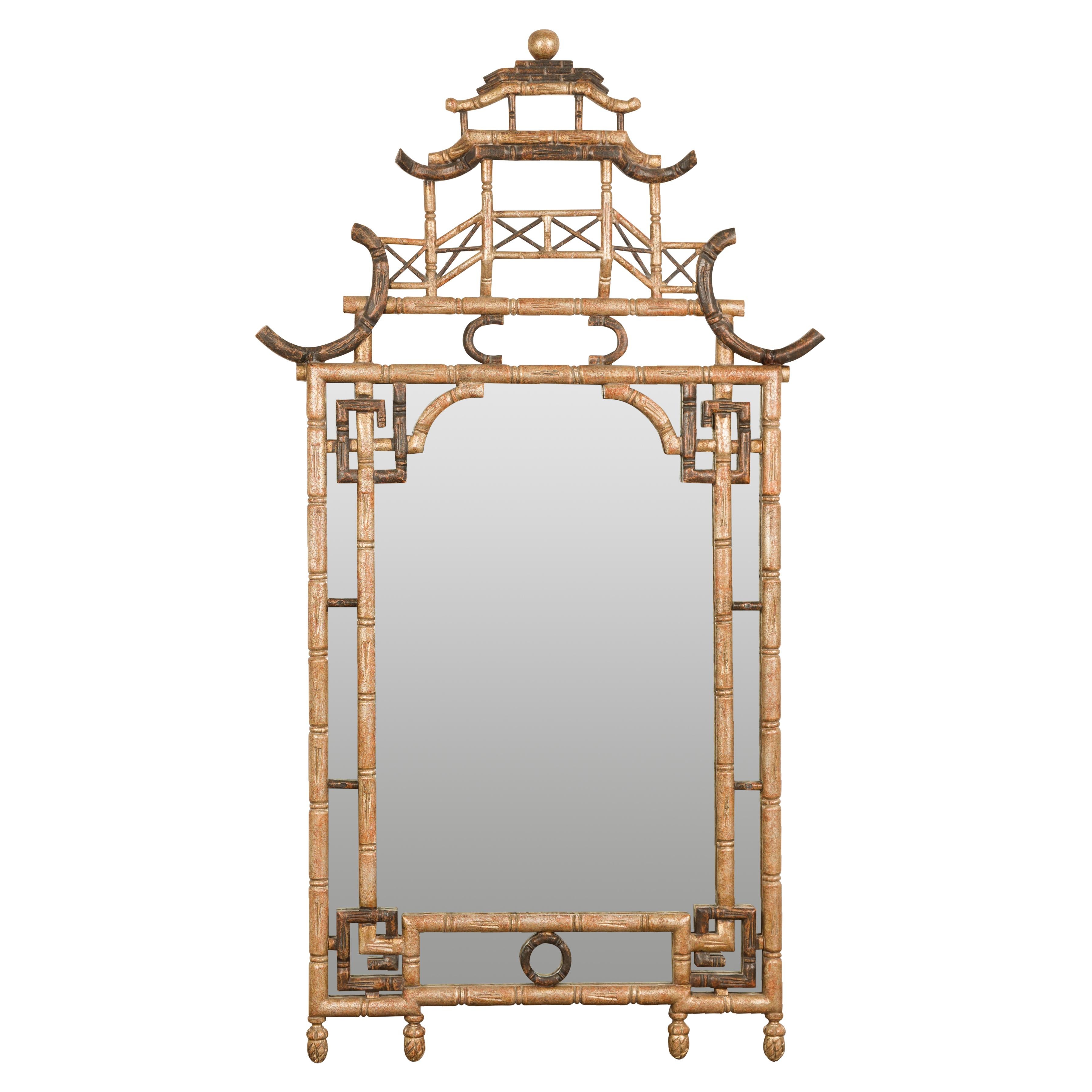 An English Pagoda mirror made of faux bamboo in the Chinese Chippendale style. Reflecting the elegant fusion of Eastern inspiration and English craftsmanship, this 20th-century Pagoda mirror epitomizes the Chinese Chippendale style. Composed of faux