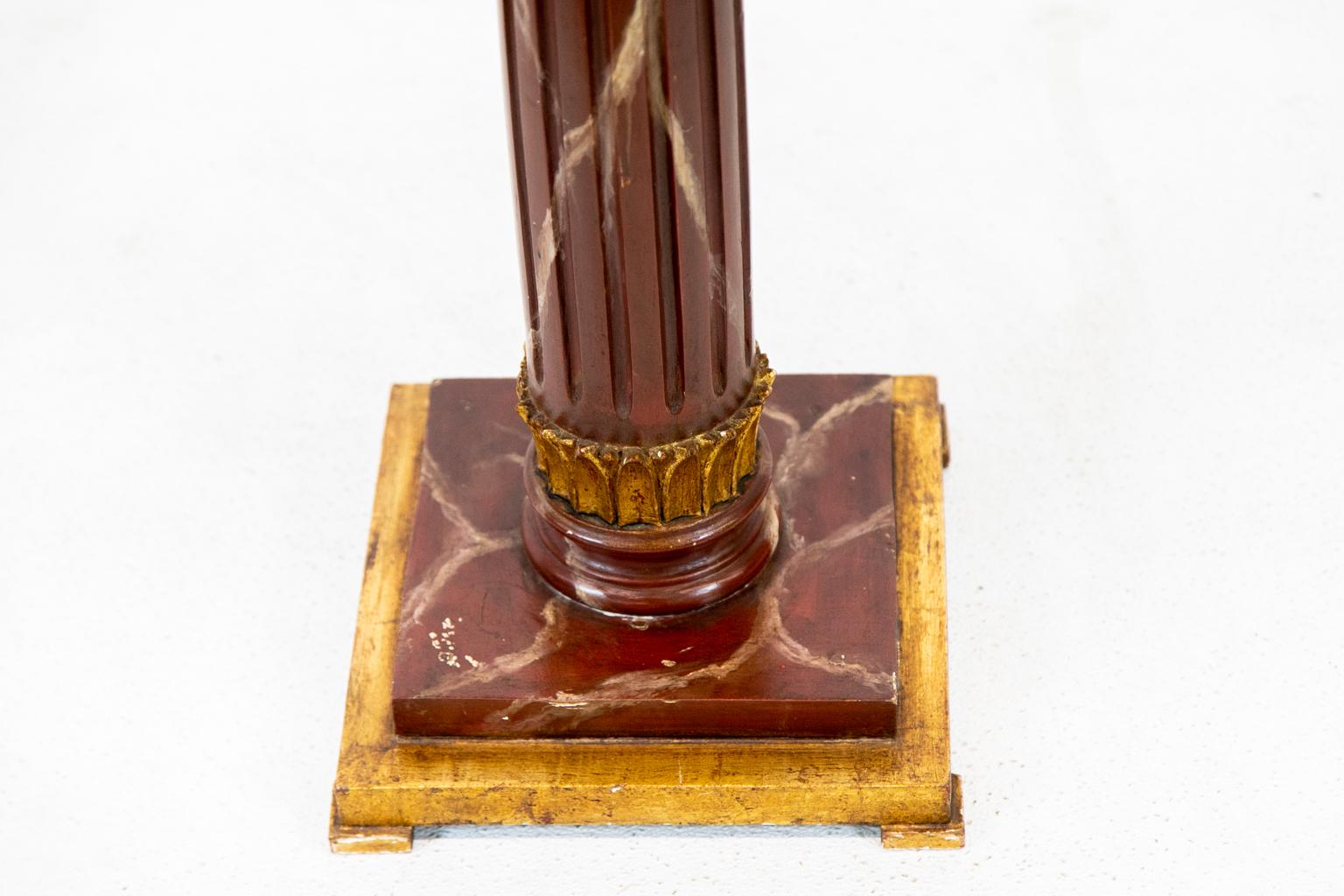 English faux marble top table is faux painted to simulate rojo Alicante marble. It has a shaped bull nose molding on the top with fluted stem and vertical leaf carving with a gilt platform base.
 