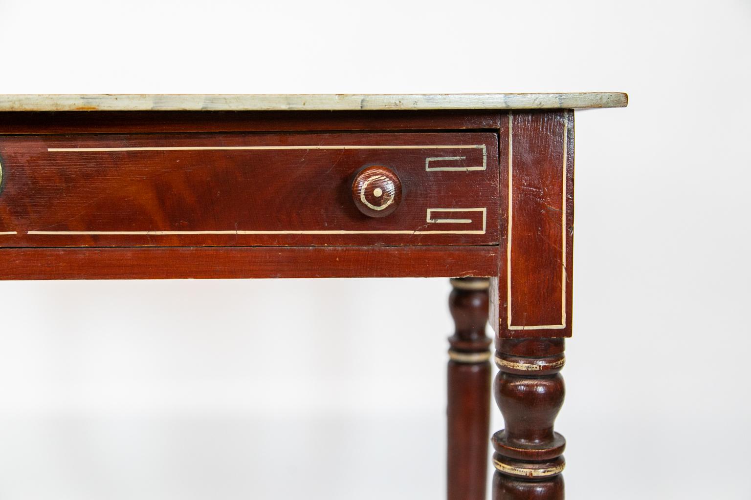 English faux painted bow front side table, with the top painted to simulate marble. The base is painted reddish brown with white painted line inlay on the drawers and sides. The turned legs are painted with white highlights. The brass escutcheon is