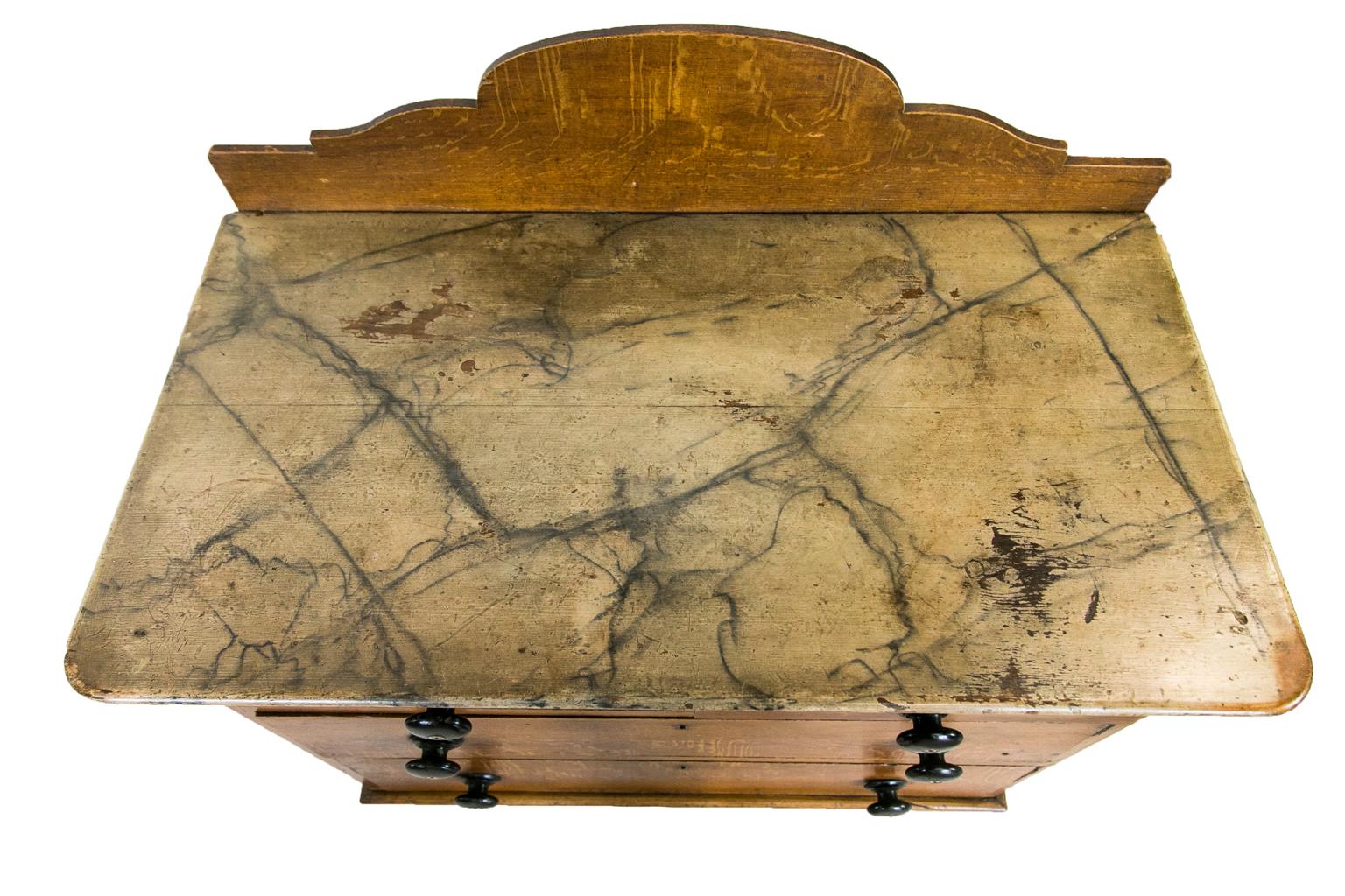 The top of this English faux painted chest is painted to mimic marble. There are areas of the top surface where the paint has rubbed through to the wooden surface. The back splash, front, and sides are painted to simulate quartersawn oak. The