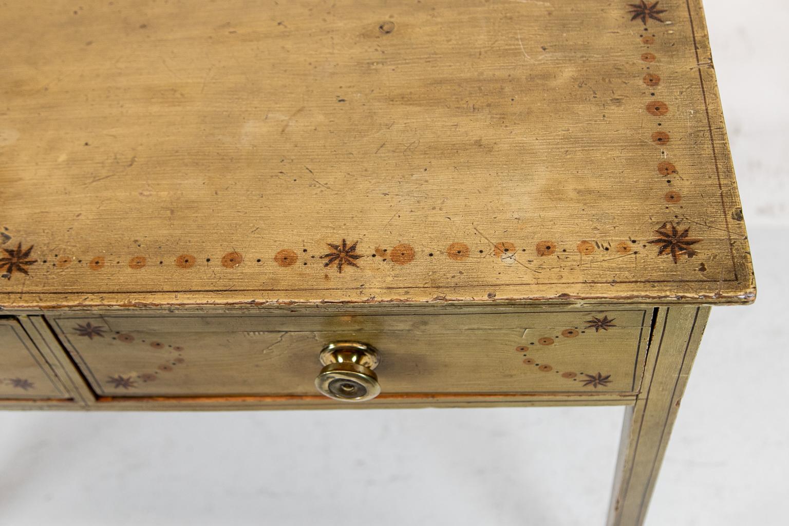 English faux painted two-drawer side table, with original brass knobs and paint. Stylized stars connected by a string of circular designs on the top and drawer fronts.