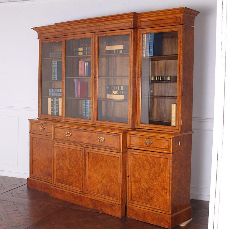 An impressive vintage English break-front bookcase in figured maple with walnut herringbone inlaid details and a fitted secretary desk in the middle section. An unusual choice of a lighter-colored timber makes for a refreshing take on a this formal