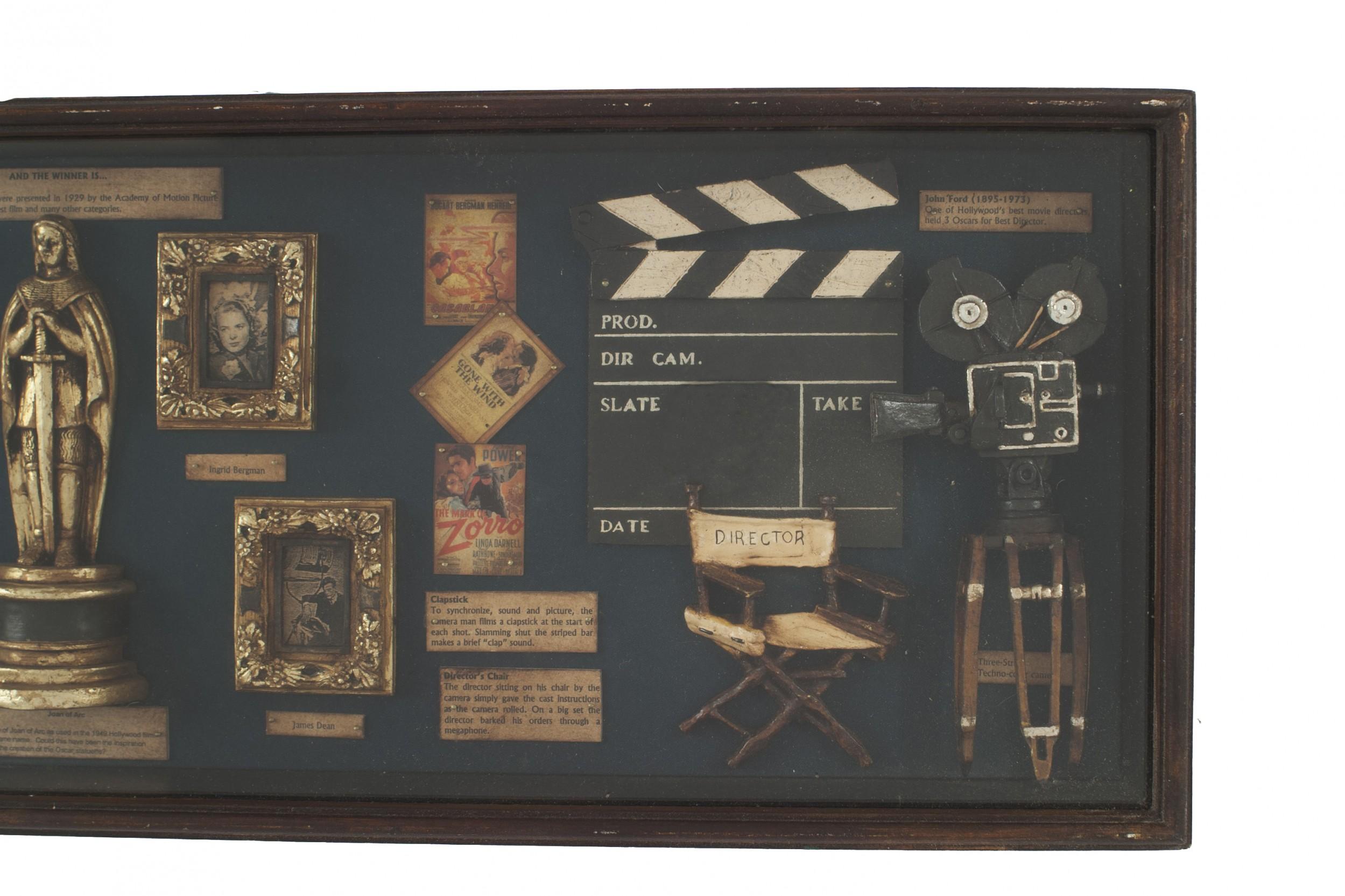 Vetrina da parete in stile inglese con fotografie delle prime star del cinema, bobine antiche e altre curiosità dell'industria cinematografica su uno sfondo di feltro verde.