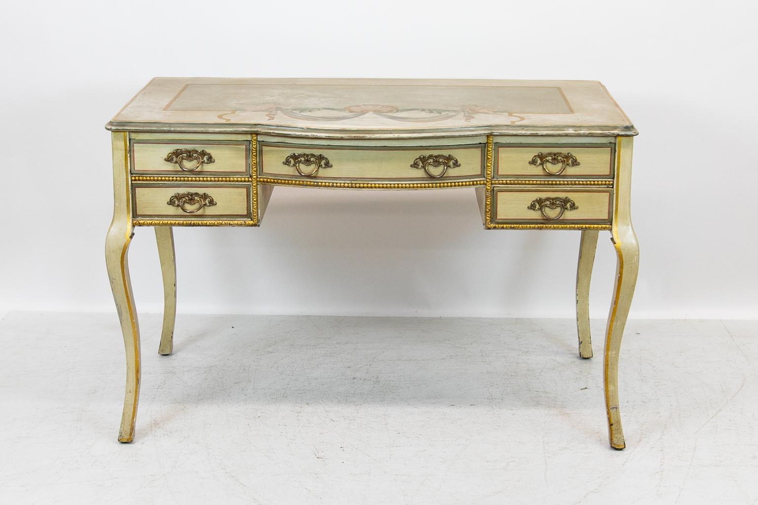 English five-drawer dressing table is painted with cupids holding swag draperies connecting to a center scallop shell. The drawers have faux painted crossbanding, and the sides have raised panels.
  