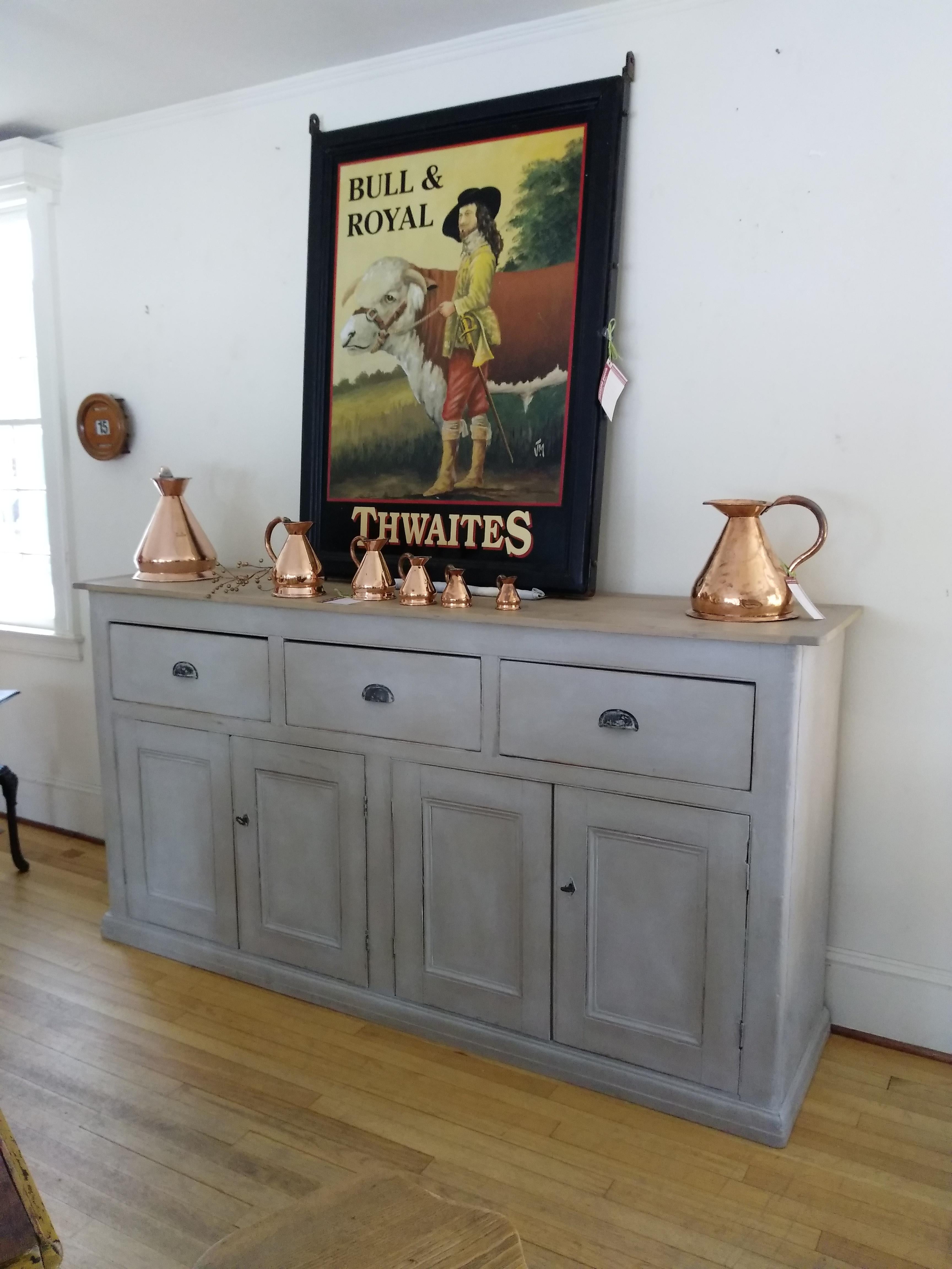 A gorgeous light grey painted English base with a light scrubbed pine top. This large piece has metal pulls on its three drawers, combined with two locks and keys for its four doors. If that weren't enough, there is also much storage space available