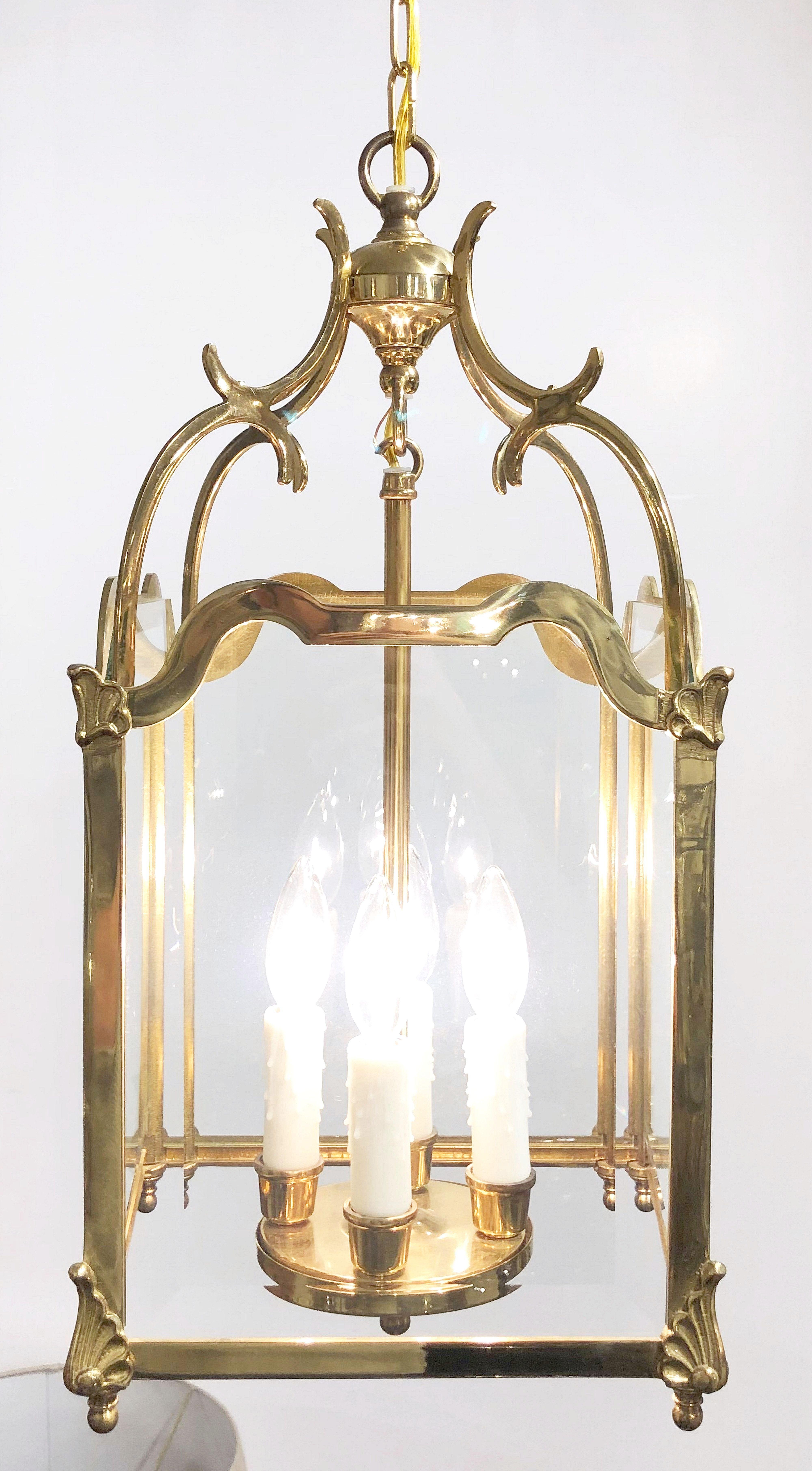 A large English four-light hanging fixture or hall or frame lantern of brass and beveled glass, featuring a four-sided body with scroll-work top and four candle lights with scroll-work top and shell motif to the corners. Decorative flourishes to top
