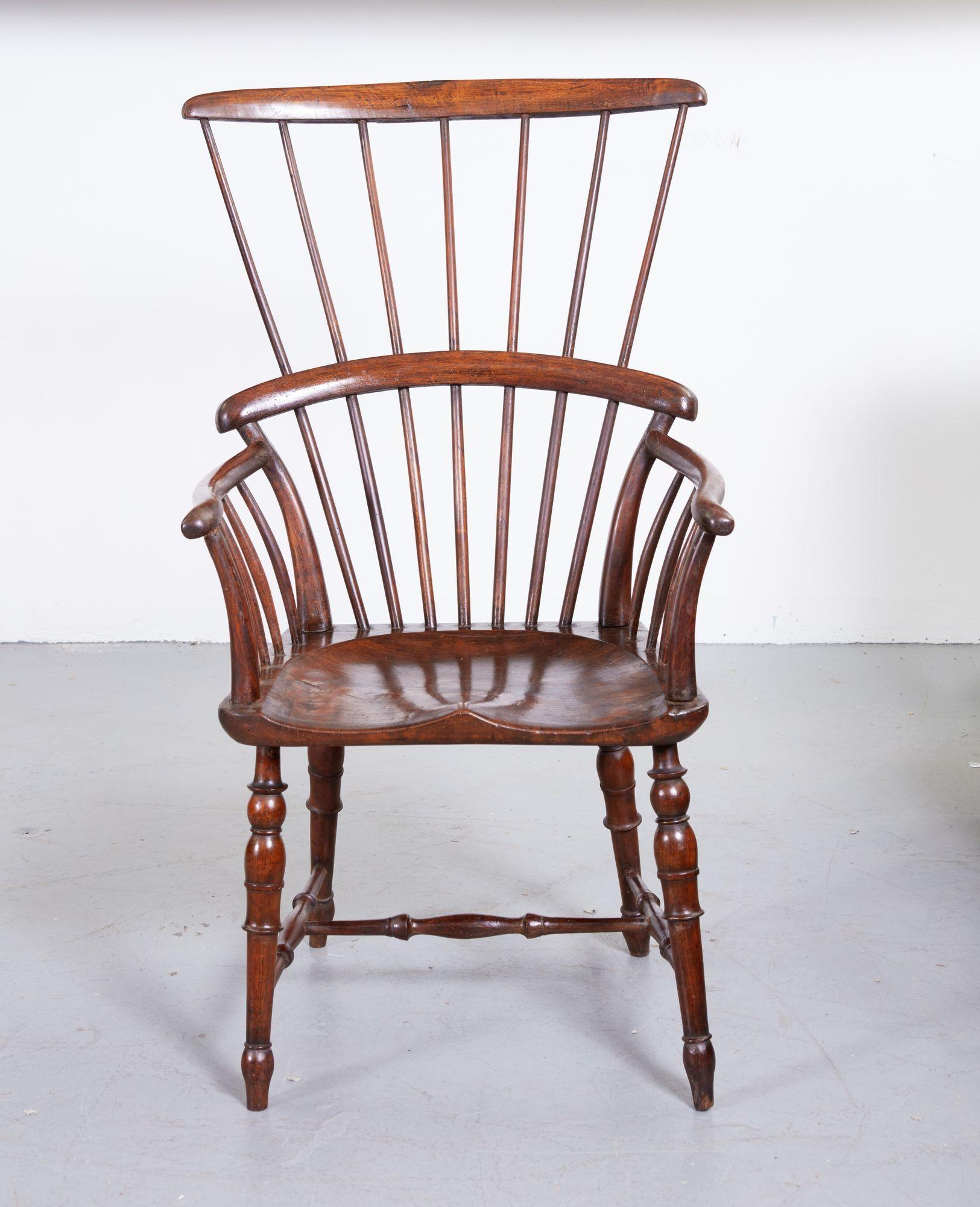 Unusual English early 19th Century fruitwood Windsor comb back armchair, the simple crest over seven flared spindles, the lower comb over curved arms supported by curved spindles over deeply saddled single plank seat, over finely turned legs joined
