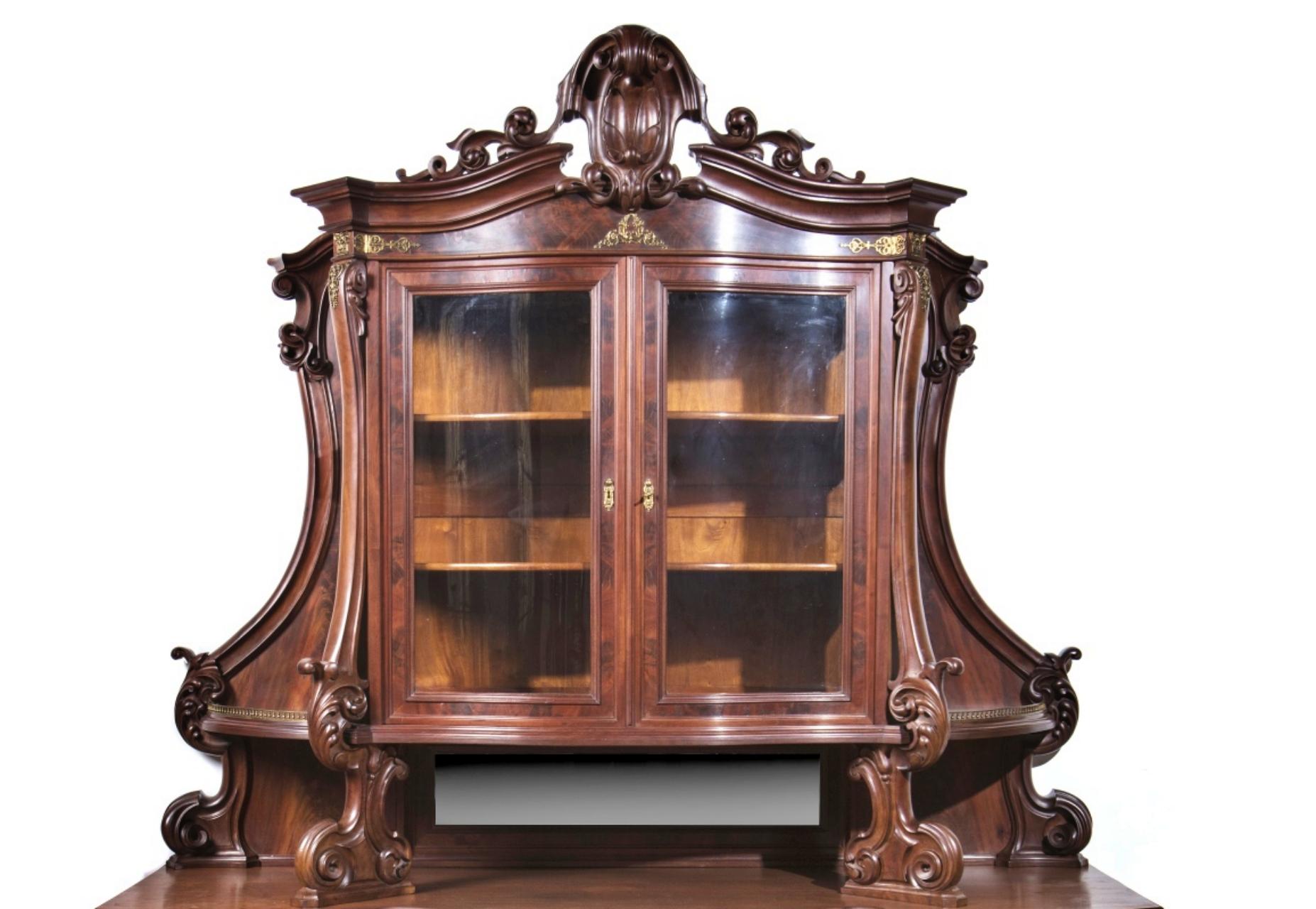 English Furniture Victorian cupboard
in mahogany wood.
Lower body with a drawer, and two doors.
Upper body with mirror, two glass doors, interior with two shelves.
Bronze applications 