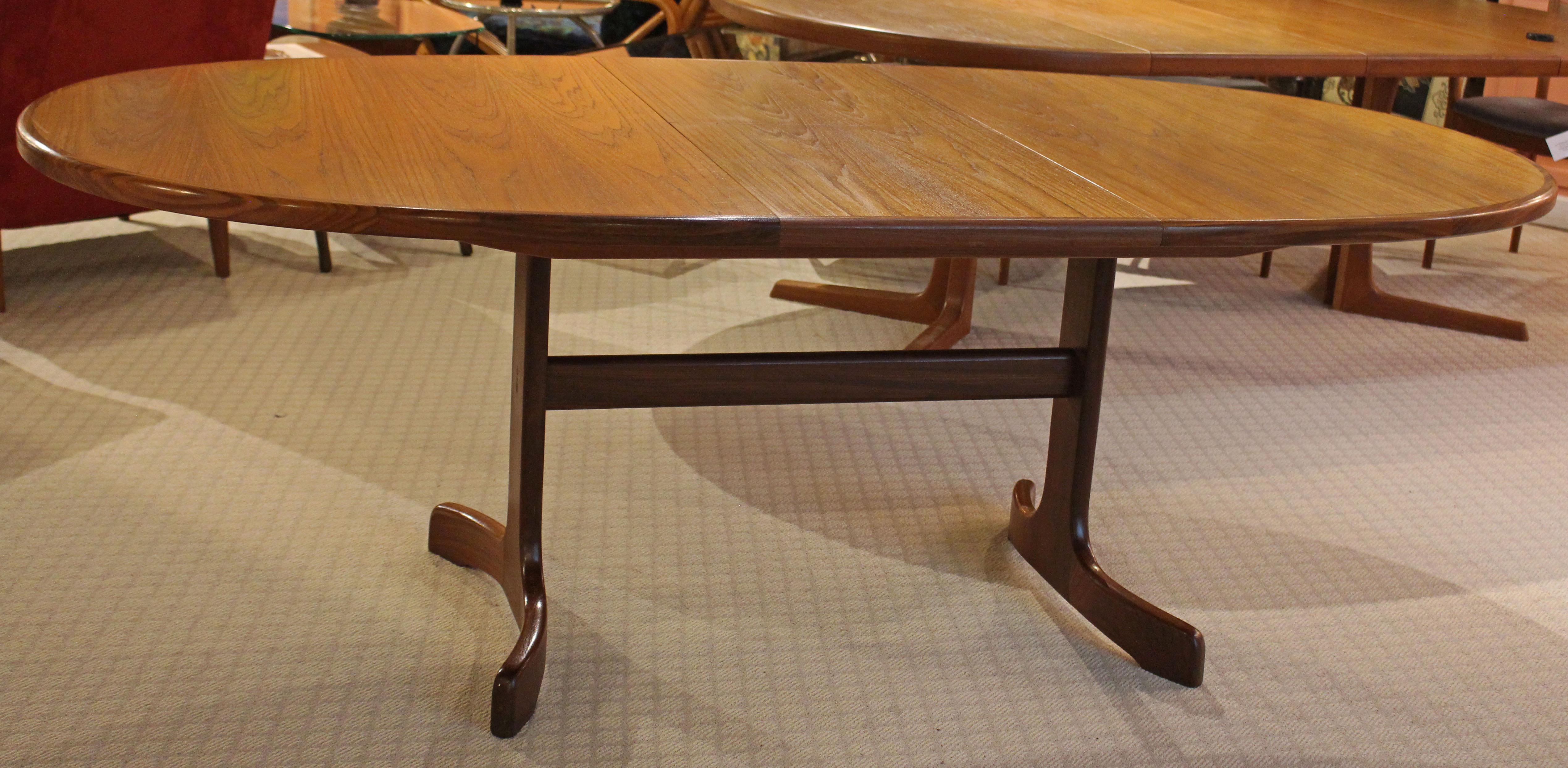 Circa 1960s Mid Century Modern extendable oval dining table. English, G-plan (label intact). Popular butterfly leaf form which stores within the table itself. Of quality teak wood with attractive contrasting surround. Trestle base with bowed