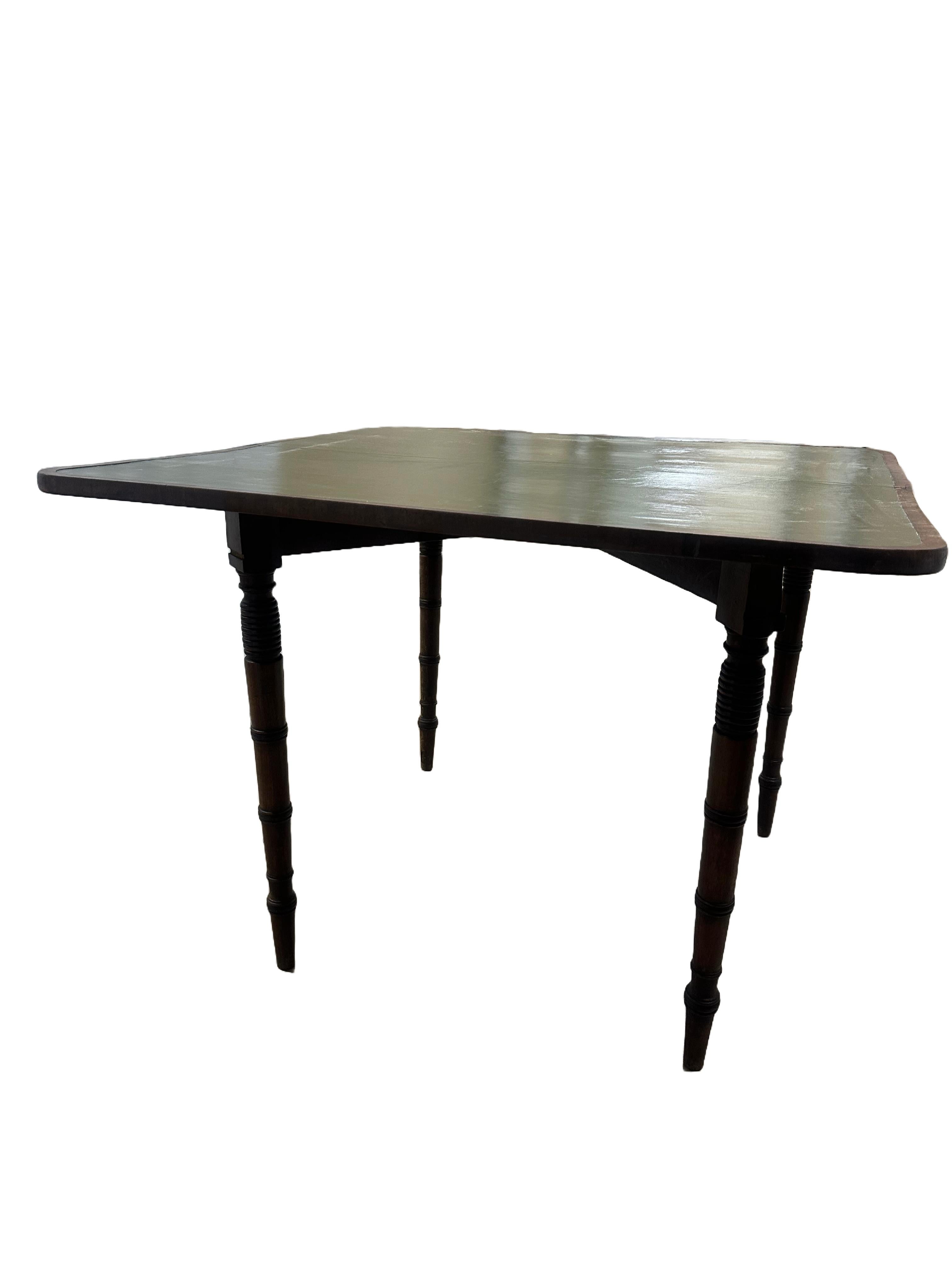 An English Sheraton Game Table with tooled and patinated leather top. This stunning game table folds open to reveal a rich olive green patinated leather top. Legs are turned. The drop-down leaves open up to unfold the table. Also doubles as a