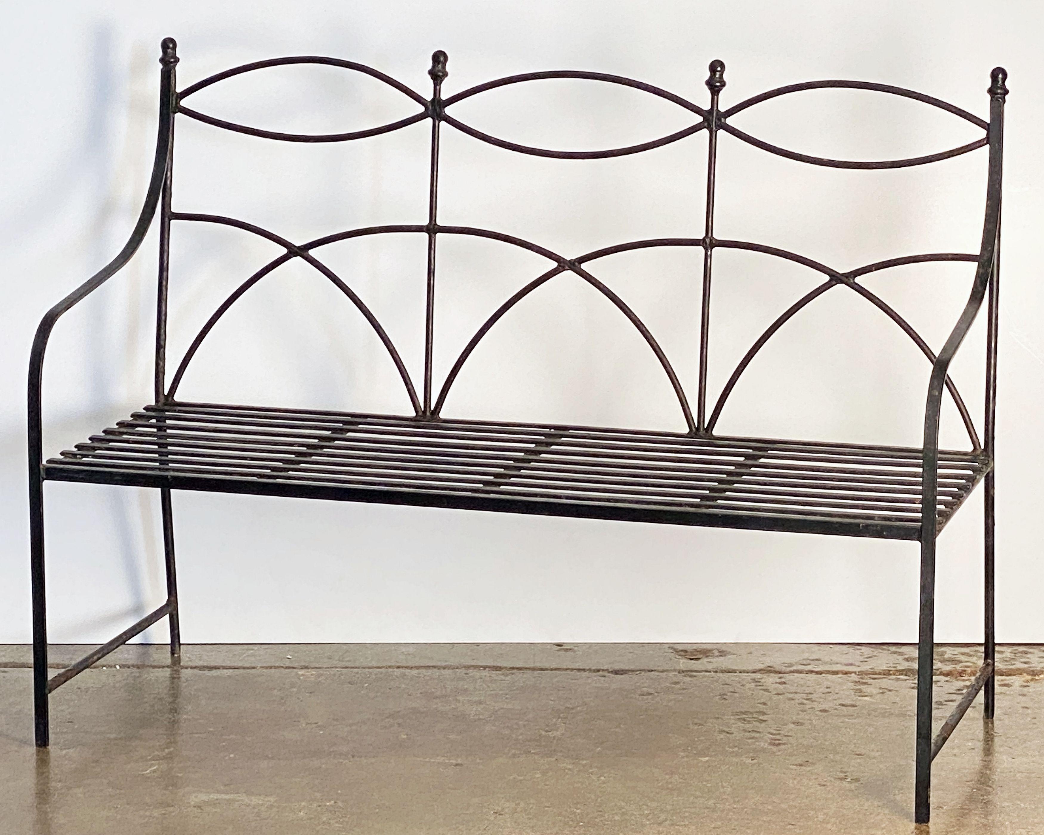 A fine English garden seating bench (or garden seat) of painted iron, featuring a comfortable back and seat with a graceful curvature and serpentine arms, with decorative finials, and set upon four legs.

Perfect for an indoor or outdoor garden,