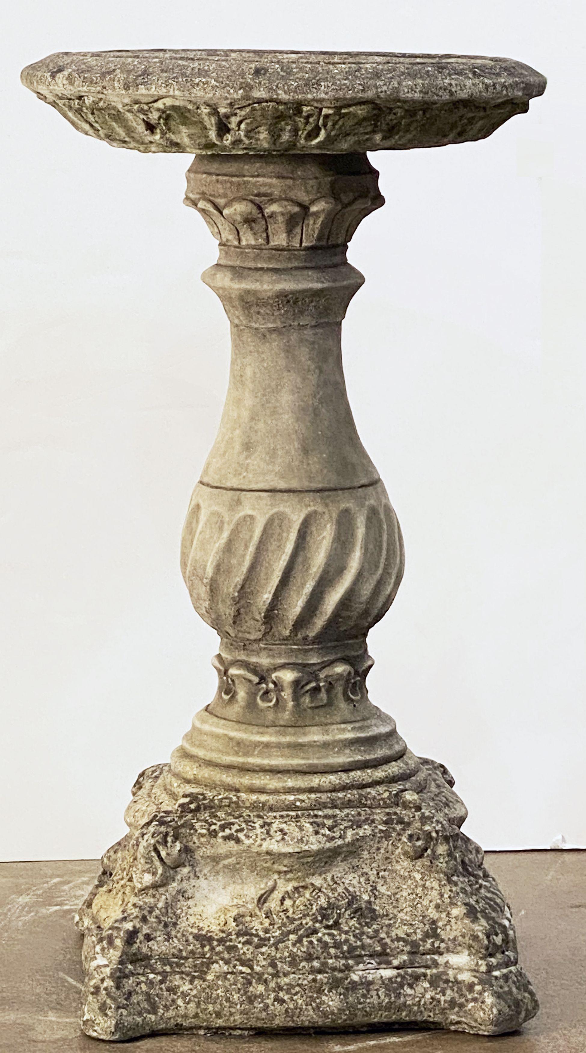 A fine English bird bath (or birdbath) of composition stone, featuring a 17 1/4 inch diameter basin top (circular) with a Classical baluster column plinth support, over a baluster pedestal with scroll design, set upon a stylish raised square plinth