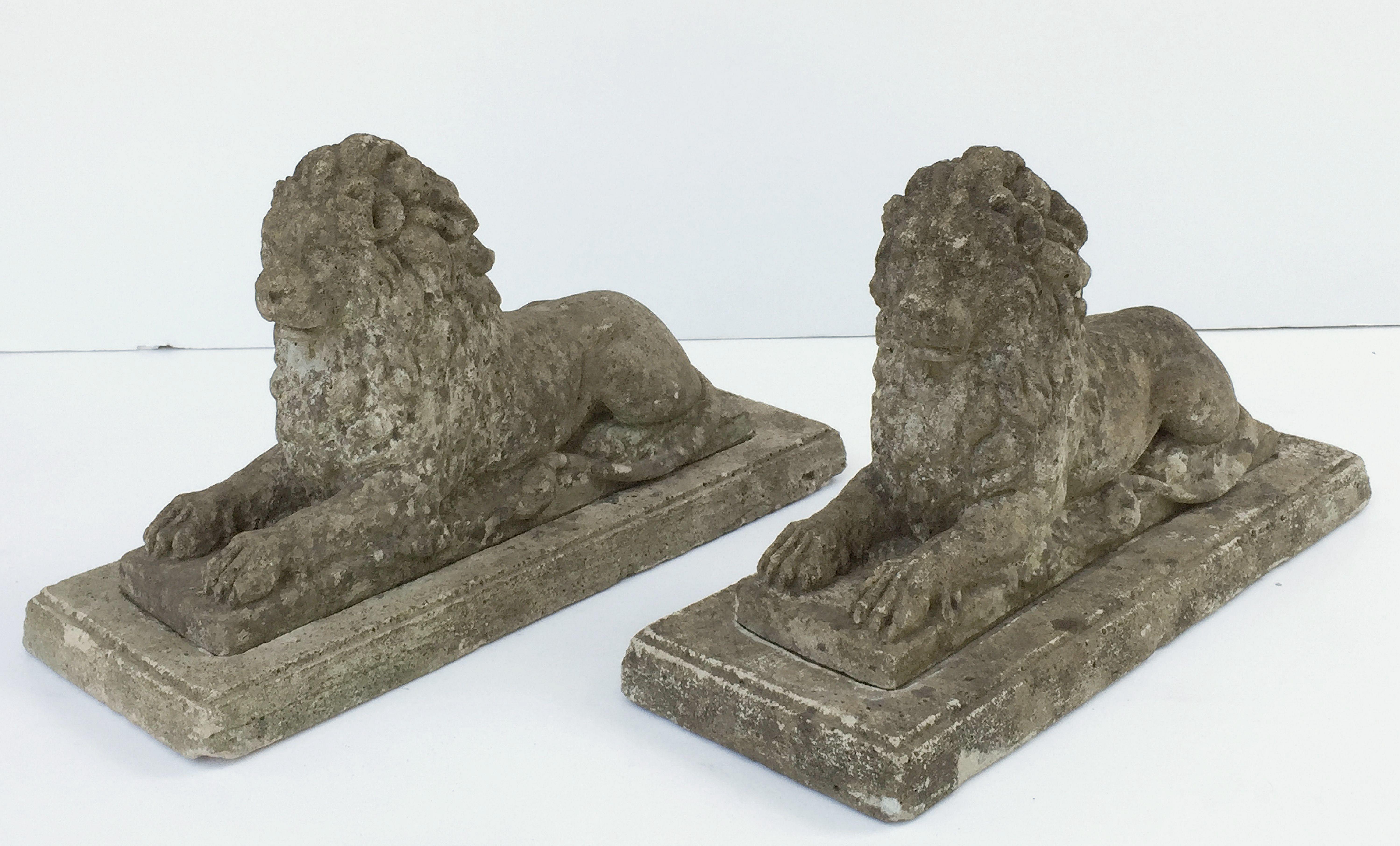 A fine pair of English garden lions of composition stone, in a recumbent pose - each lion featuring fine detail modeling, set upon a fitted, recessed rectangular base or plinth.

Dimensions of each lion: H 13 1/2 inches x W 23 inches x D 9