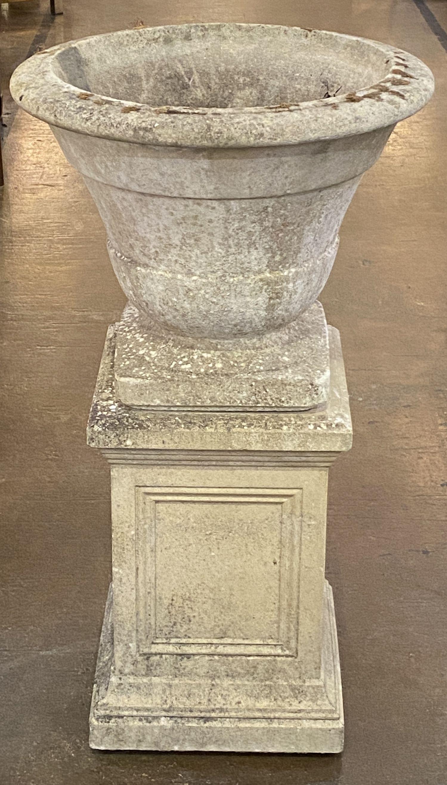 A fine English garden urn (or planter pot) on plinth of composition stone, featuring a round urn with Classically proportioned body on raised square base, set upon a square plinth with a paneled design to the sides.

Perfect for a garden room or
