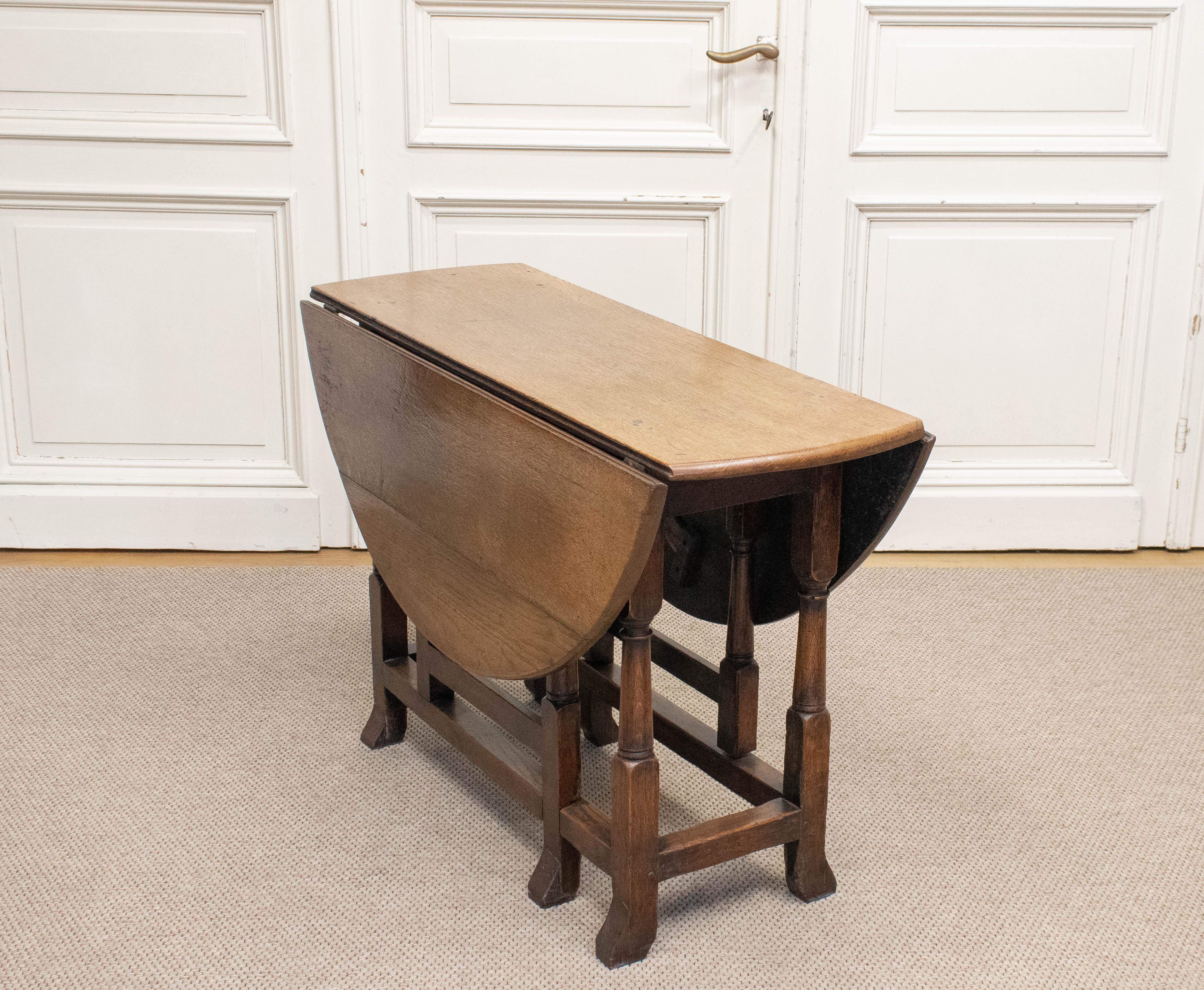 Beautiful English oak drop-leaf table, dating from circa 1880, crafted with traditional wooden peg (mortise-and-tenon) joints and still retaining its original iron hinges.
The table features two hinged leaves that can be raised to form a generous