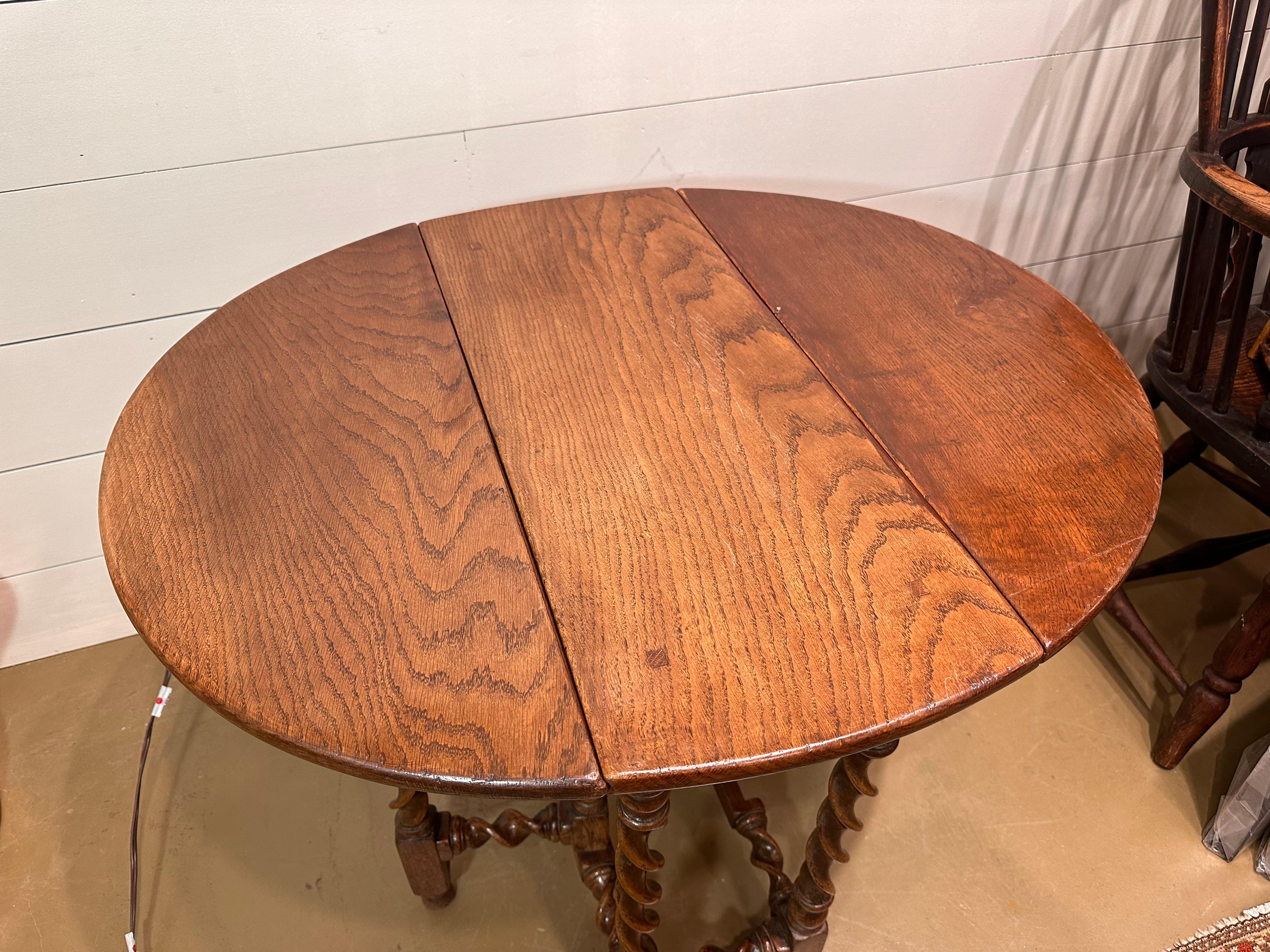 This charming 19th-century English gate leg table embodies a timeless design and practical elegance. Crafted with deep and rich wood, it unfolds to reveal a spacious surface, perfect for both everyday meals and special gatherings or even as an