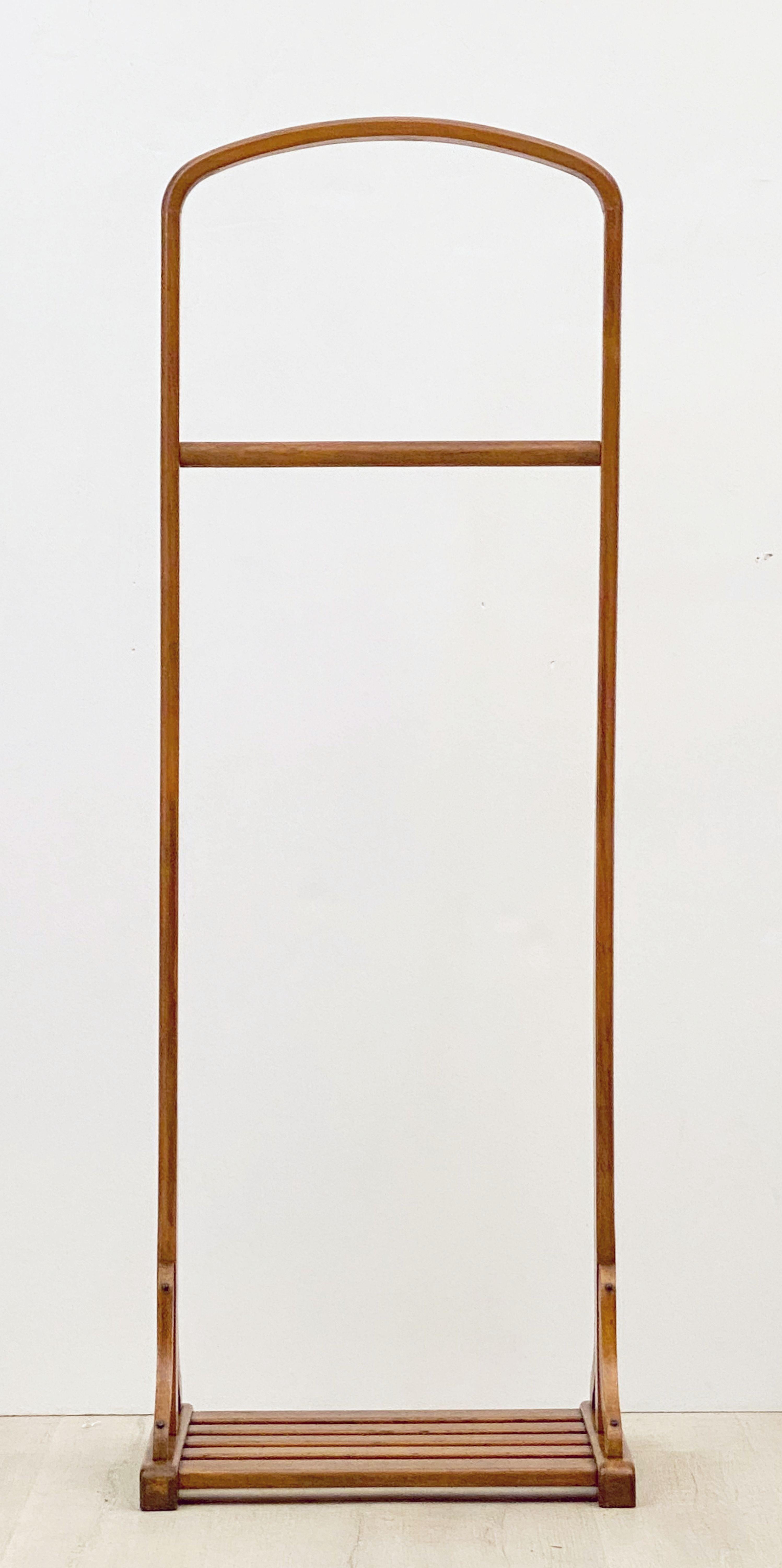 A fine English gentleman's valet or suit and coat stand clothing rack, featuring a curved bar top over a tie bar and resting on a slatted base.
