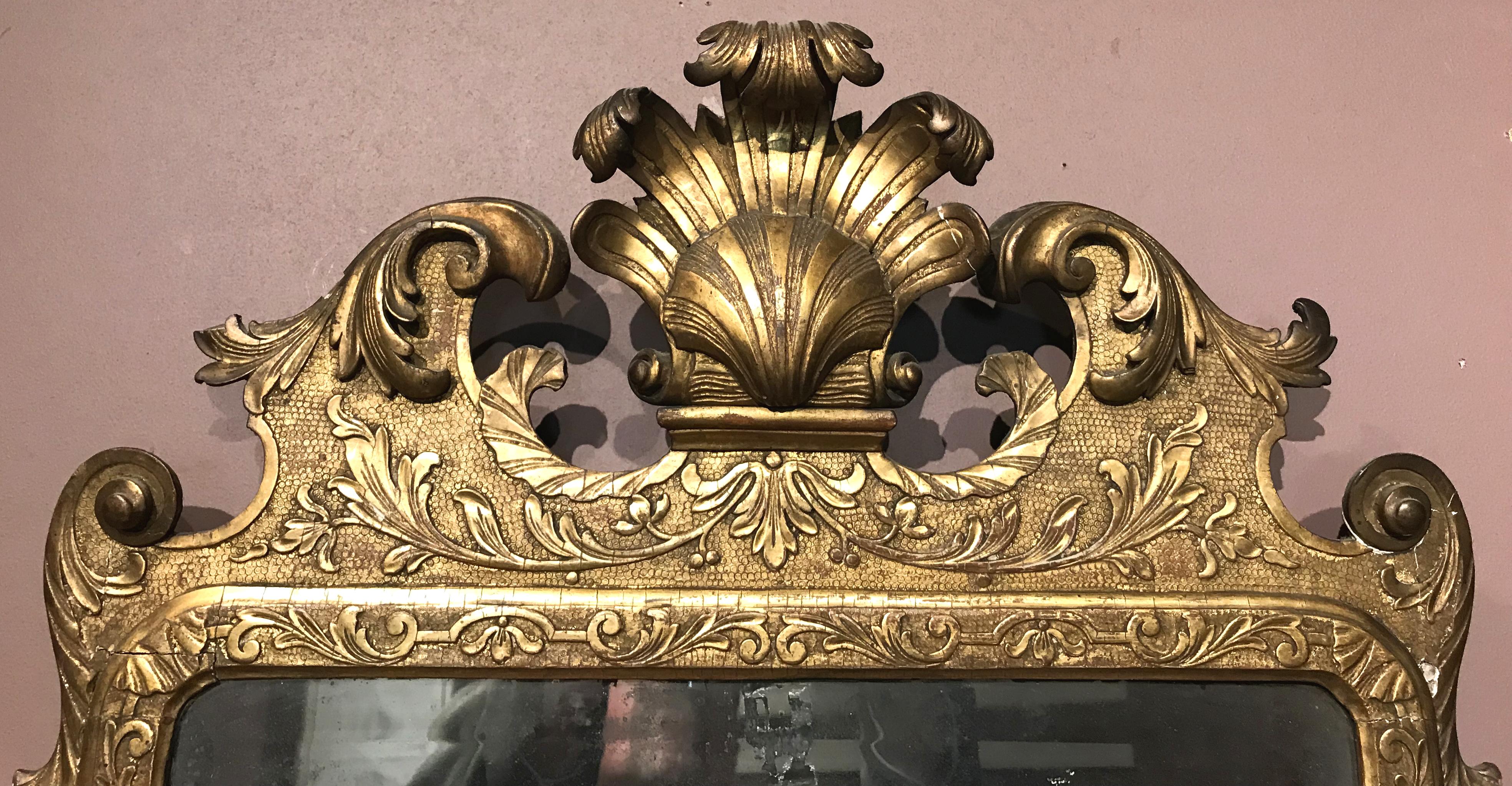 A fine English George I giltwood mirror or looking glass with shell and Prince of Wales feather decoration on the crest, scroll and foliate carved surround, and possible original mirror plate, circa 1725. In very good overall condition, with minor