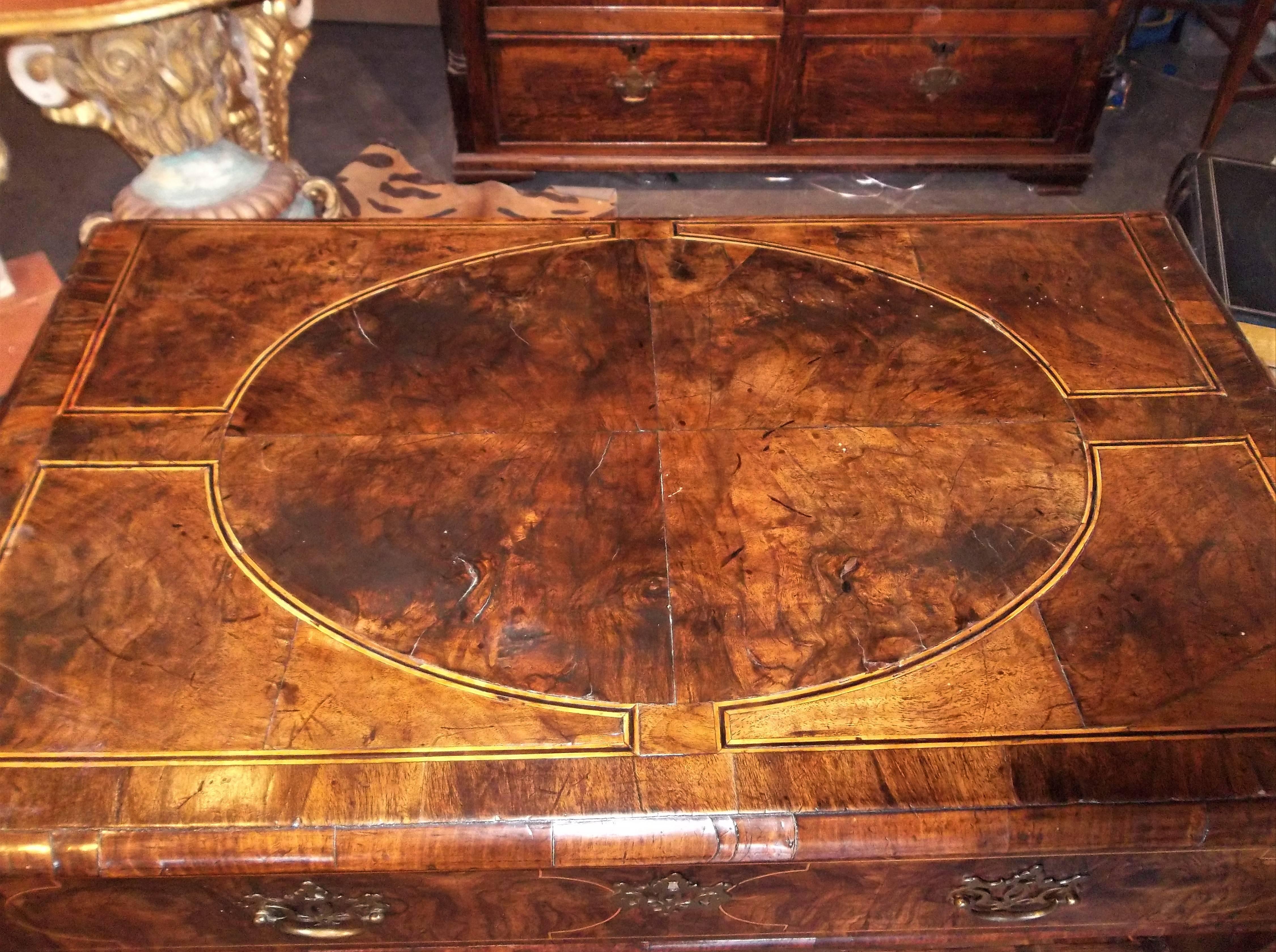 On bracket feet. The top and drawer fronts with string inlay. Heavily grained walnut burl veneers. Drawers with evidence of earlier pulls, current bat wings probably 19th century. Nice rich color overall. Fine patina. Thick chunky hand-carved