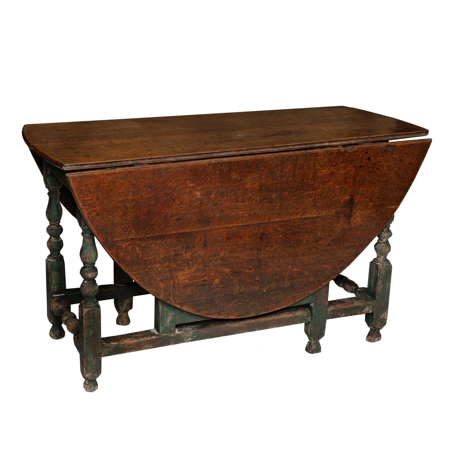An English George I period oval oak gate leg drop-leaf table with single drawer and dark green painted under-carriage, circa 1720. 
(paintwork refreshed)

Measures: Height 73cm (28.5