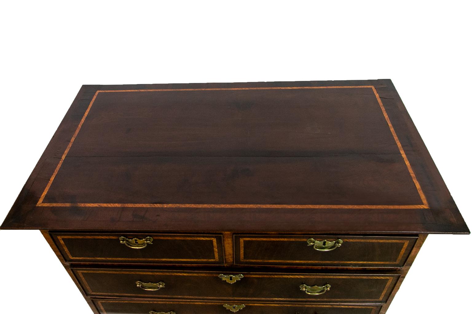 English George II chest, has the original hardware and is crossbanded with elm. There is some shrinkage cracking on the top.