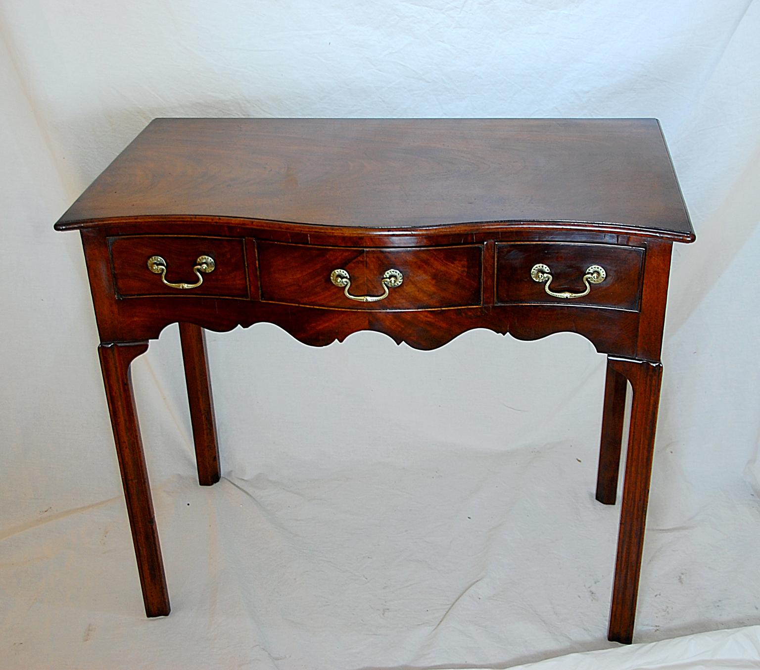 English George II period Chippendale mahogany dressing table. This fine table has a serpentine carcass as well as top. The three drawers are veneered, the center drawer with bookmatched mahogany, the carcass is of solid mahogany, the drawers are
