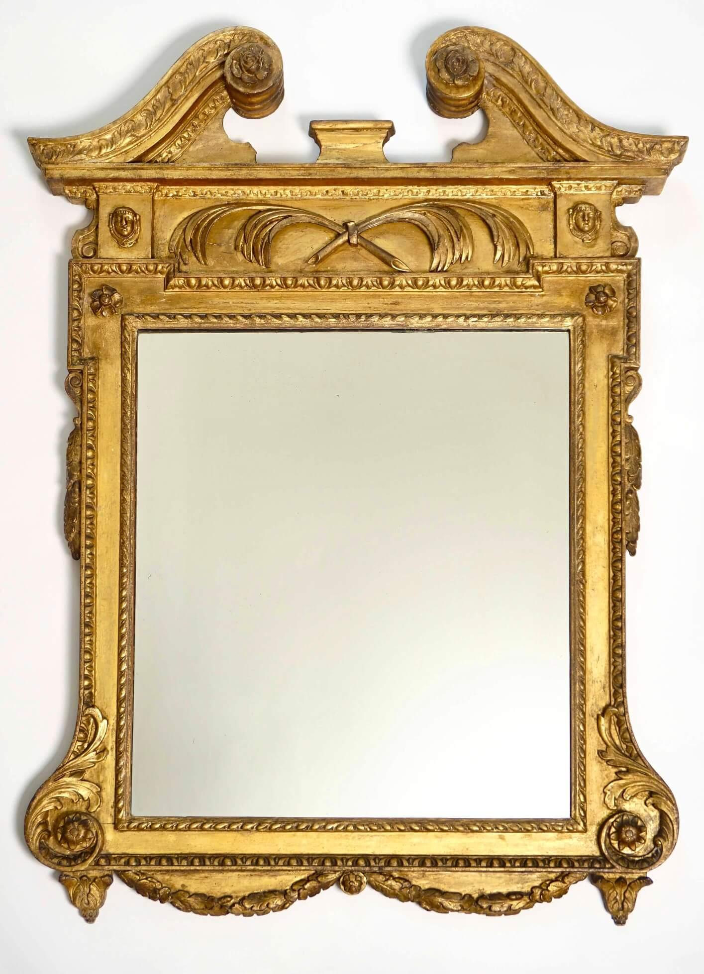 Fino espejo o mirilla inglés de principios del periodo Jorge II, de hacia 1735, a la manera palladiana del arquitecto y diseñador William Kent (1685-1748), con marco de madera tallada en dorado original y frontón de volutas o 