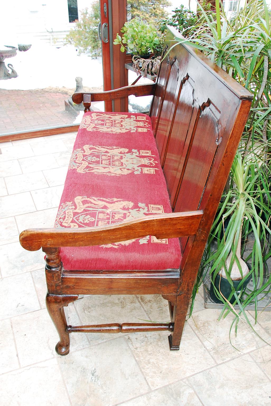 English George II period oak paneled back settle with upholstered seat. This settle has four fielded shaped panels which form the back. There are shrinkage cracks to the panels, but they have been repaired and in one case reinforced from the back of