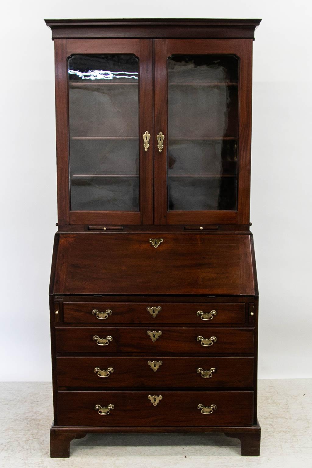 The top section of this secretary has three adjustable shelves and has two candlestick pullouts. The interior has a raised panel prospect door flanked by two carved fluted pilaster pullout compartments. There are six small drawers below six cubby