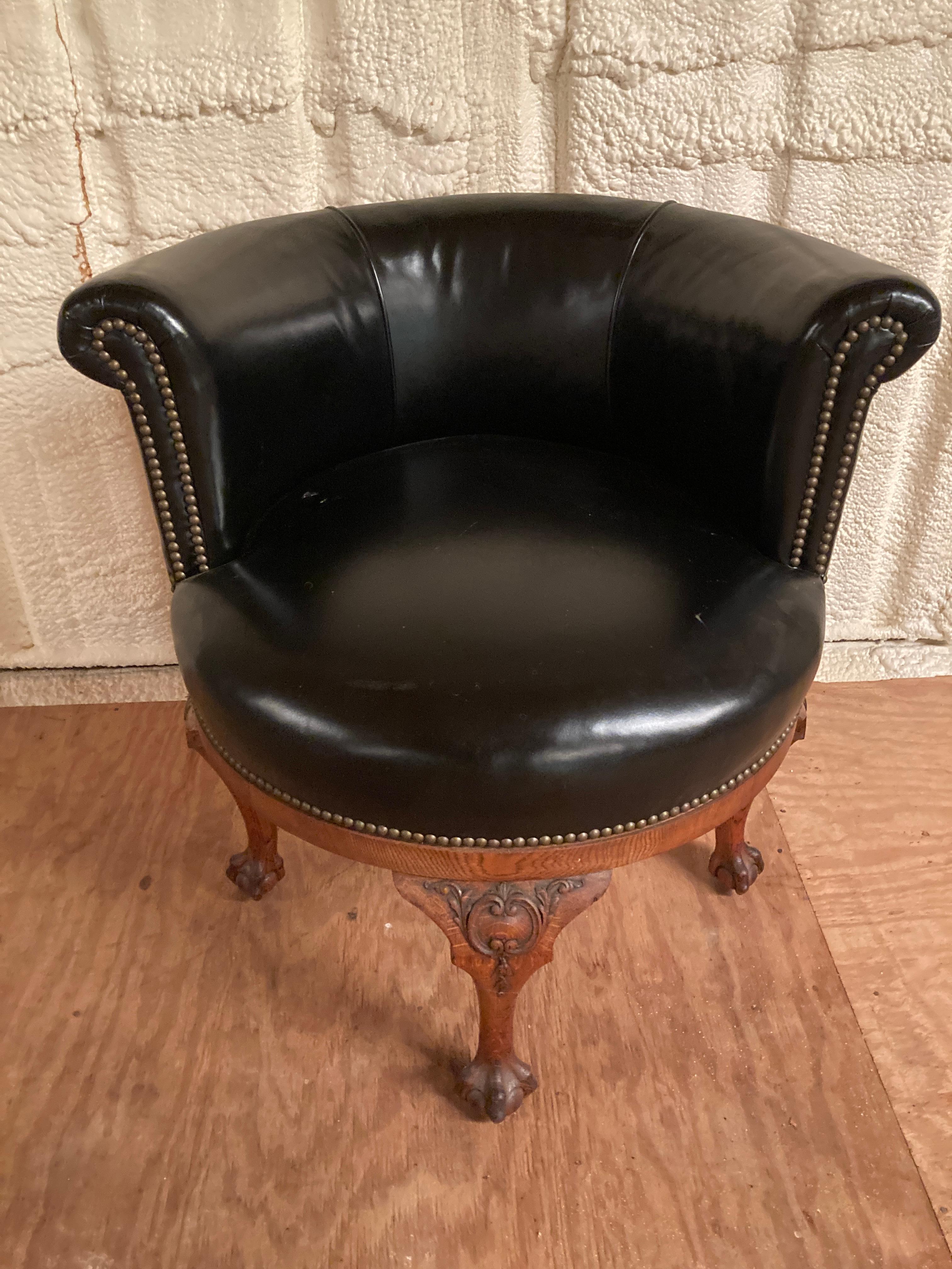 Georgian style swivel desk chair with claw and ball feet and nice carving. This English armchair is currently upholstered in black faux leather with nailheads and has a few small flaws. This flexable chair could be used in many locations and is