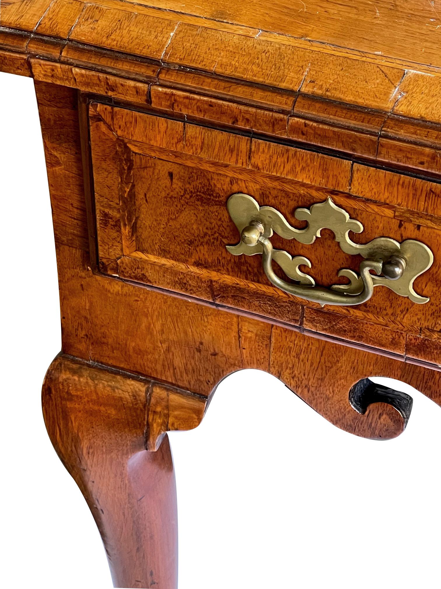 the rectangular quarter-veneered top with banding and molded edge over a burlwood frieze drawer above a scalloped apron; all raised on cabriole supports ending in pad feet.