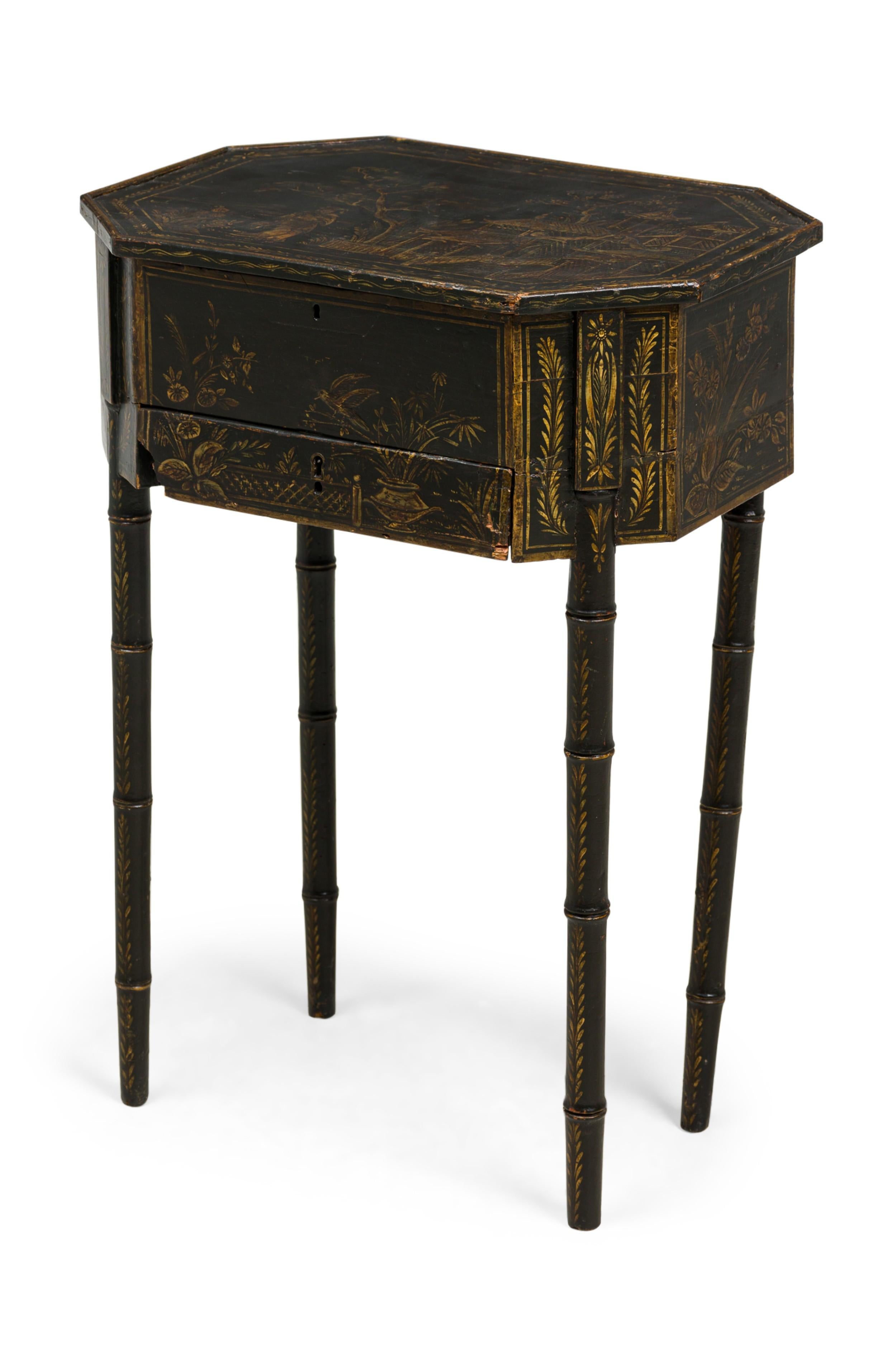 English George III Black Japanned work / end / side table with an elongated hexagonal cabinet, having a lid decorated with a gilt genre scene which opens on hinges to reveal an open interior compartment above two lower drawers, resting on four faux