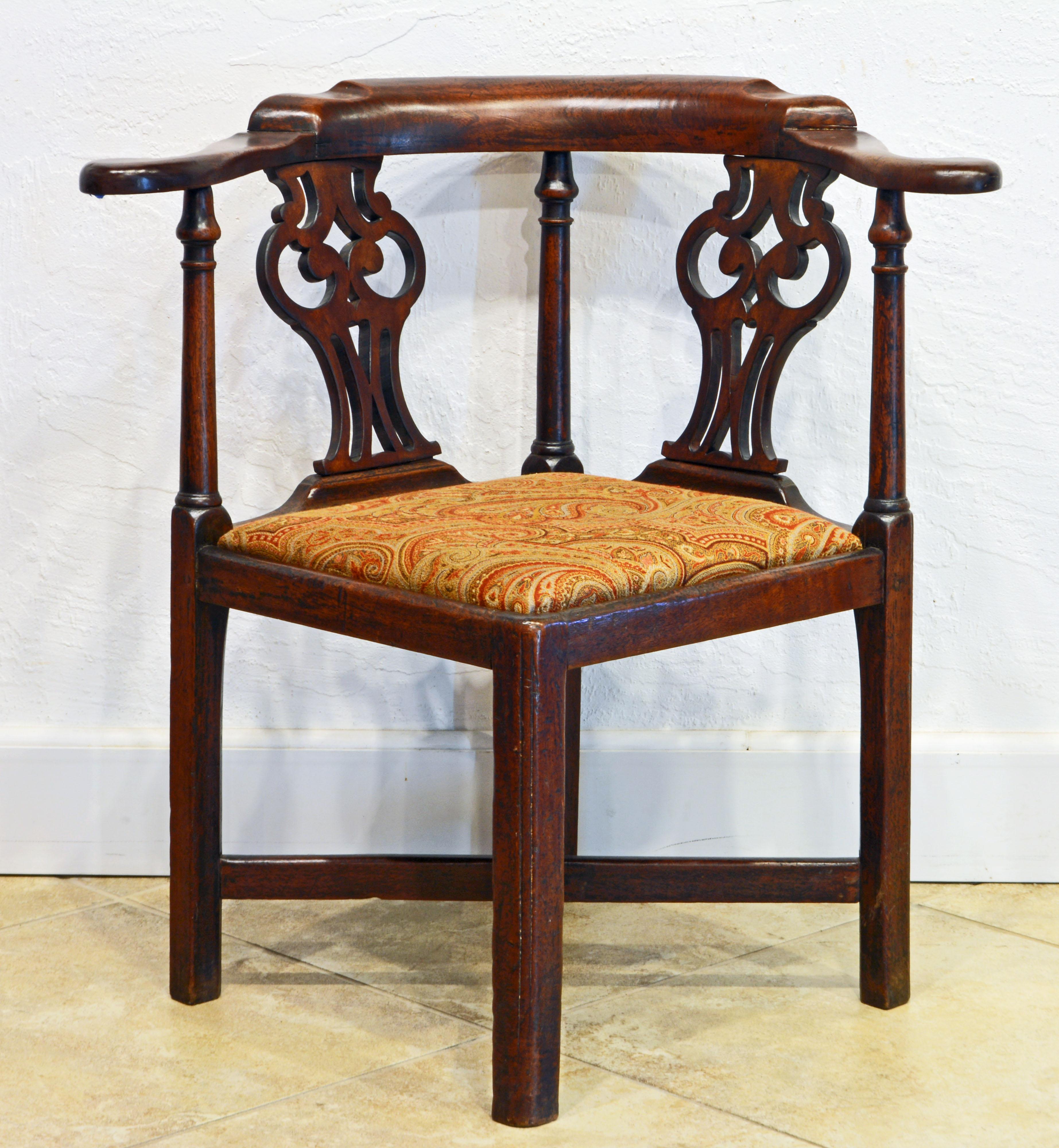 This English late 18th century Georgian period Chippendale corner chair features intricately carved splats, out curving armrests, cross stretchers, square molded legs and upholstered removable slip seat, circa 1790.