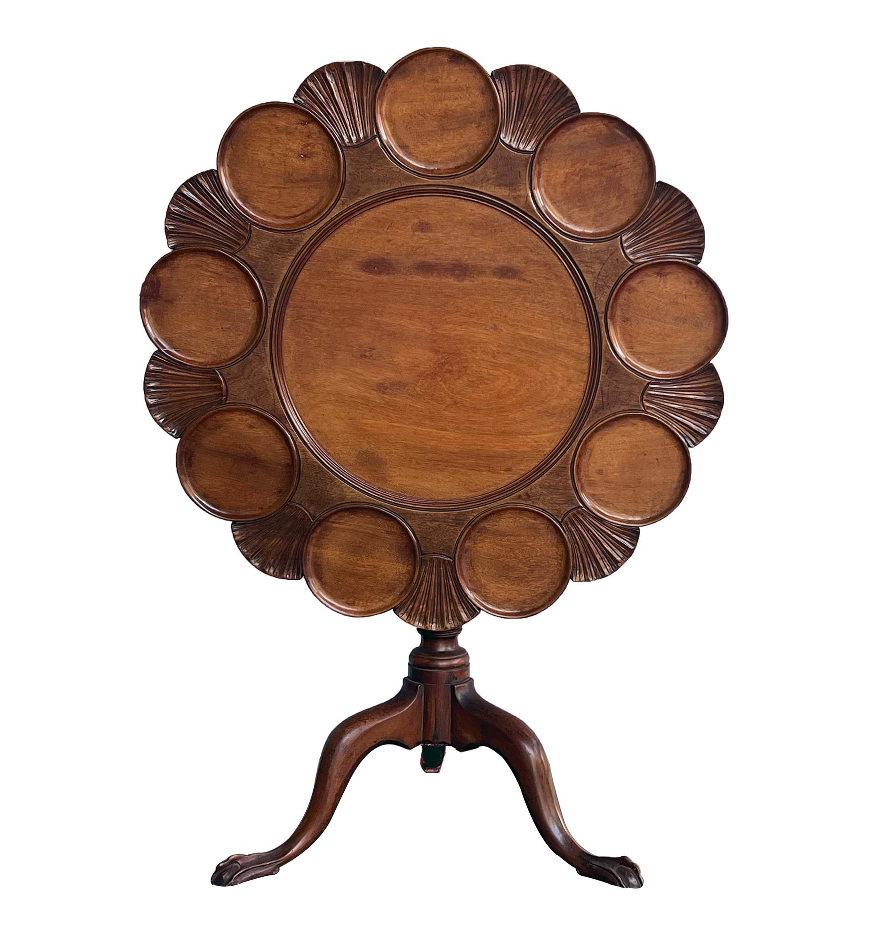 a wonderful period English George III hand-carved tilt-top supper/tea table with shell and leaf carved top with circular reserves, over a turned baluster support issuing three downswept legs terminating in ball and claw pad feet; the English supper