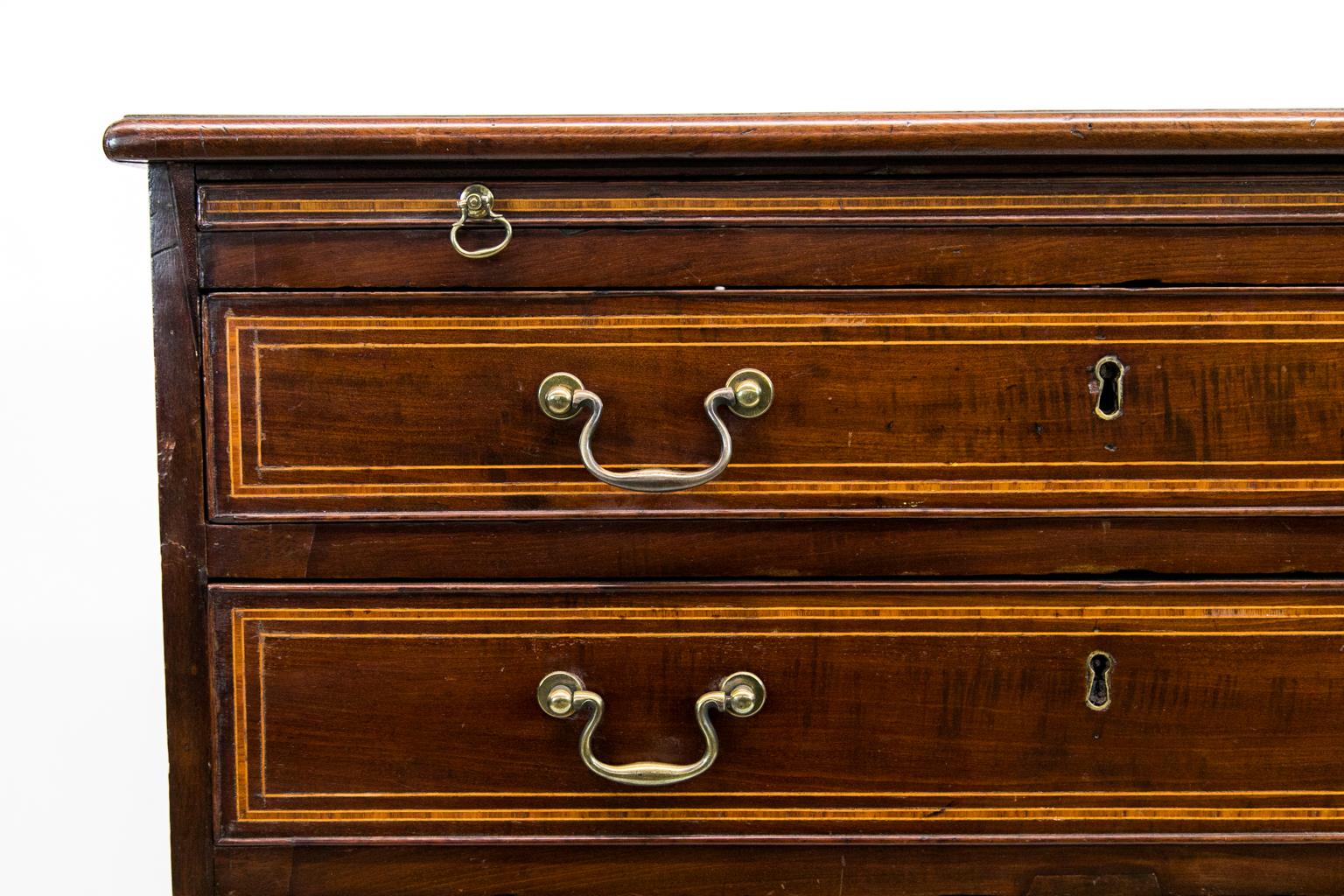 English George III inlaid bachelor's chest, with the top and drawer fronts cross banded and inlaid with satinwood and boxwood. The drawer fronts are veneered with tiger mahogany. The finish and hardware are original. It has a functioning brushing