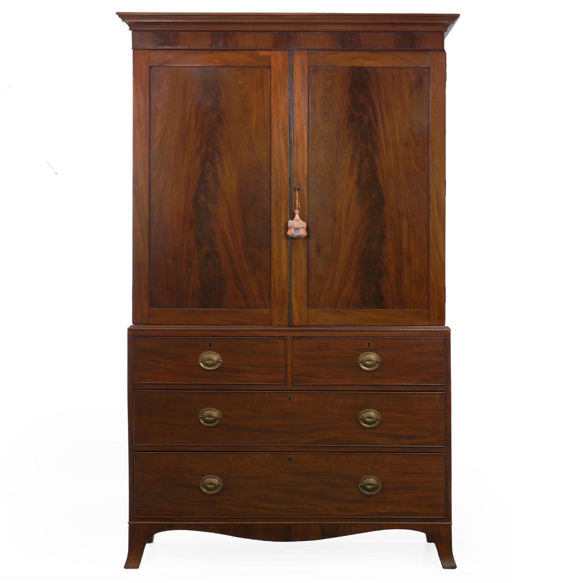 A gorgeous linen press from the turn of the 19th century, being a product of England circa 1790-1810, it is perhaps most notable for the incredible crotch-mahogany panels in the pair of linen doors beneath the cove molded crest. The doors open to