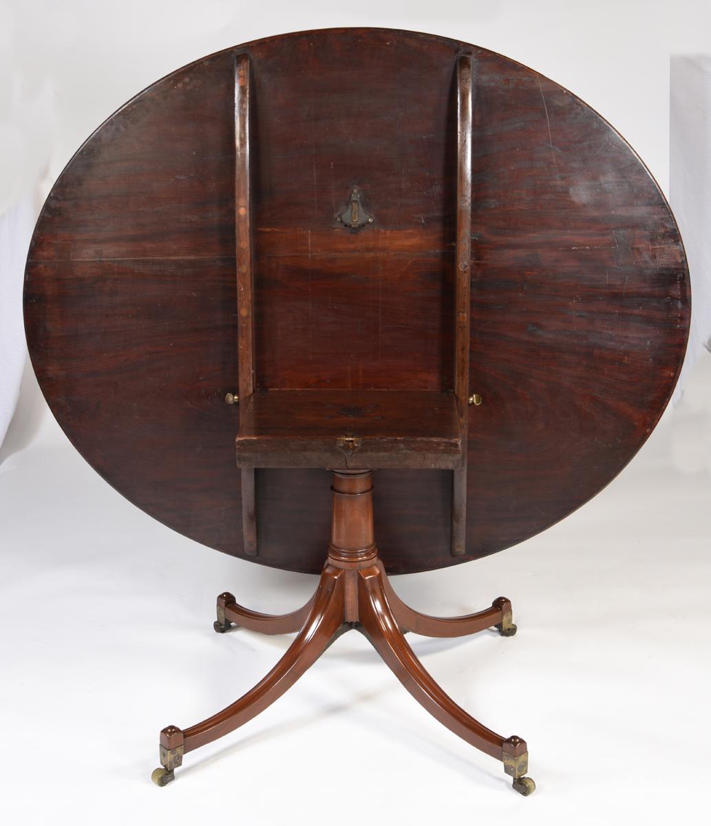 Impressive antique English large oval Cuban mahogany breakfast table on a four splay pedestal base. The tilting top is made from the finest Cuban mahogany with a tulipwood crossbanding. Made and stamped by the well-known company, Gillows of