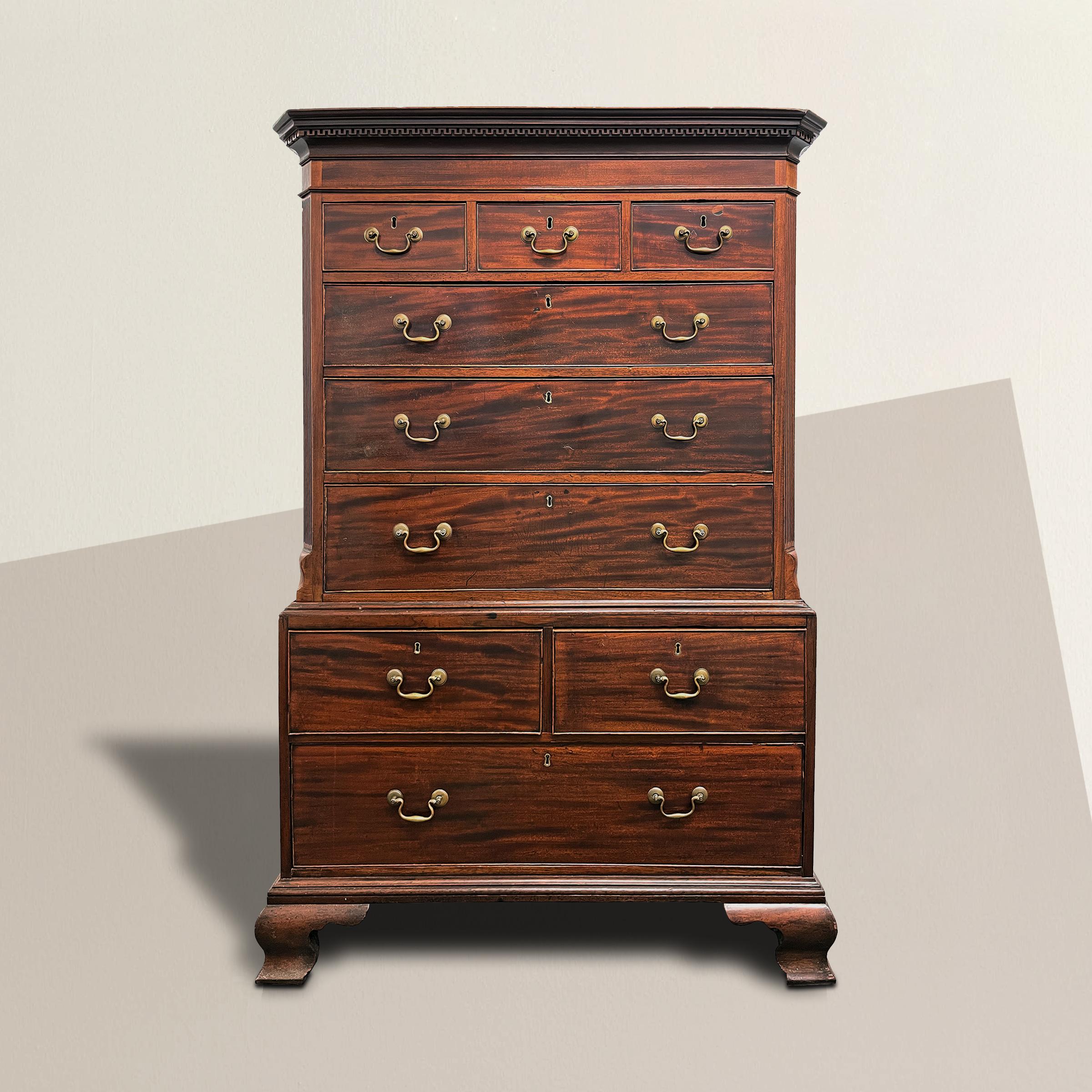 A striking 18th century English George III period figured mahogany chest on chest with a simple entablature with a Greek key cornice, fluted chamfered corners, and nine drawers each with brass pulls, and supported by bold scrolled feet. The perfect