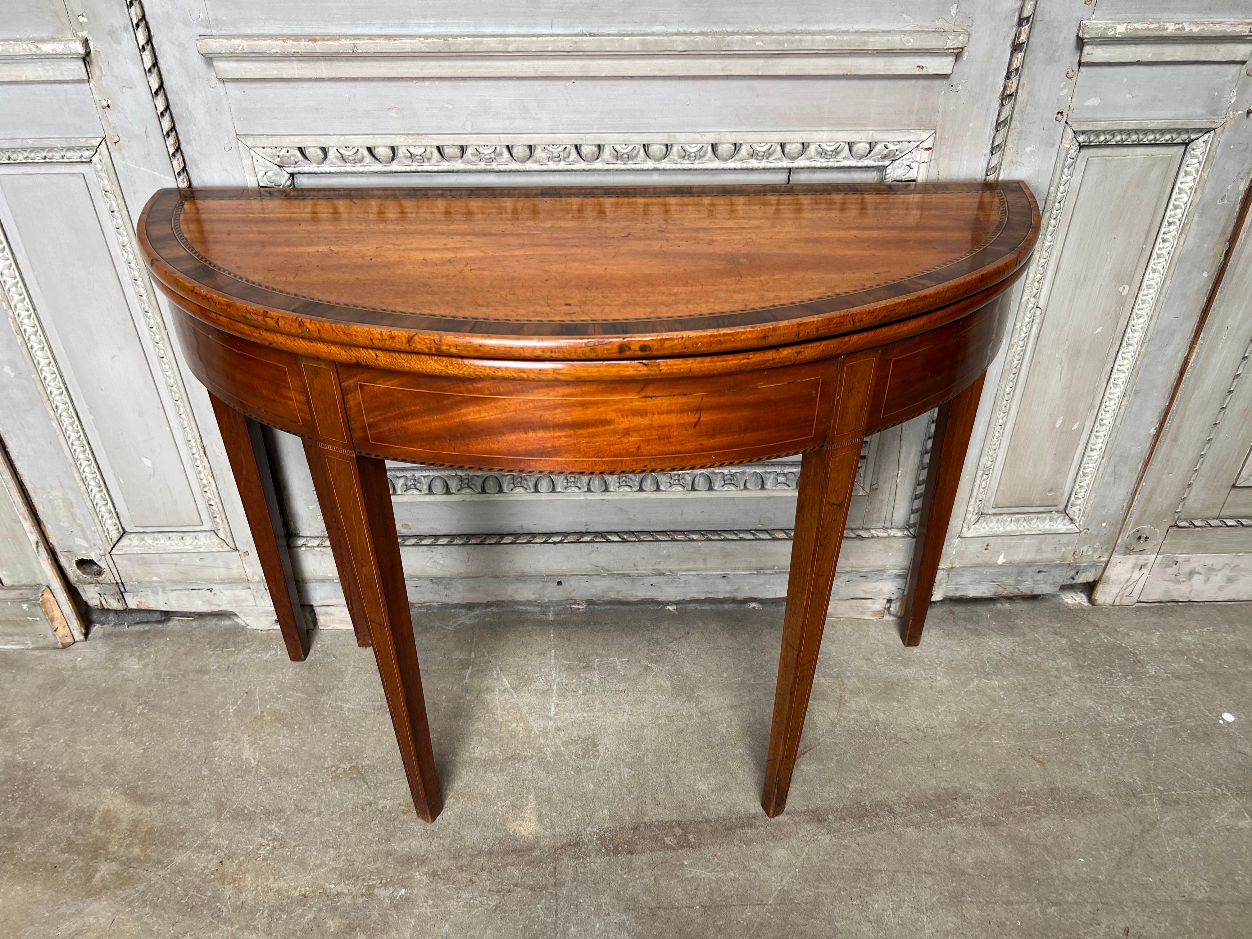 An English George III mahogany demi-lune gate leg game table with a lovely old patina and color.  This small scaled demi-lune is a perfect cosole in a small tight spot and would be very useful for extra seating during a party.  