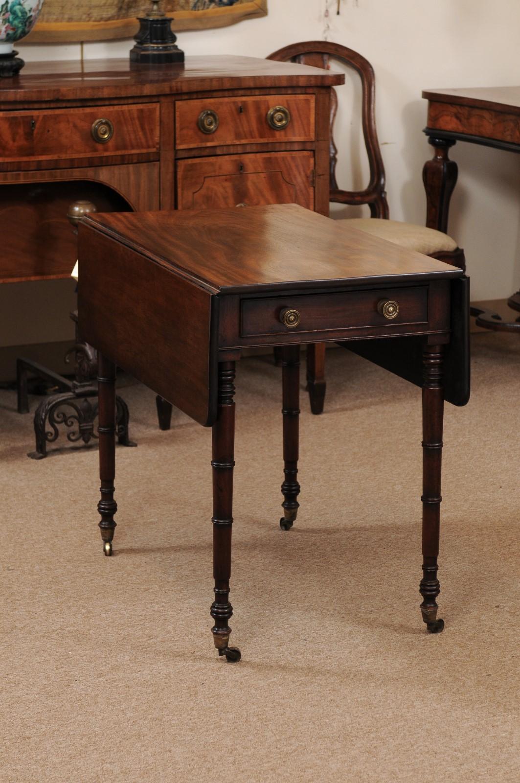 An English George III figured mahogany pembroke table featuring one drawer with brass pulls, turned legs ending on brass castor feet, ca. 1800. 

The dimension are 39.5
