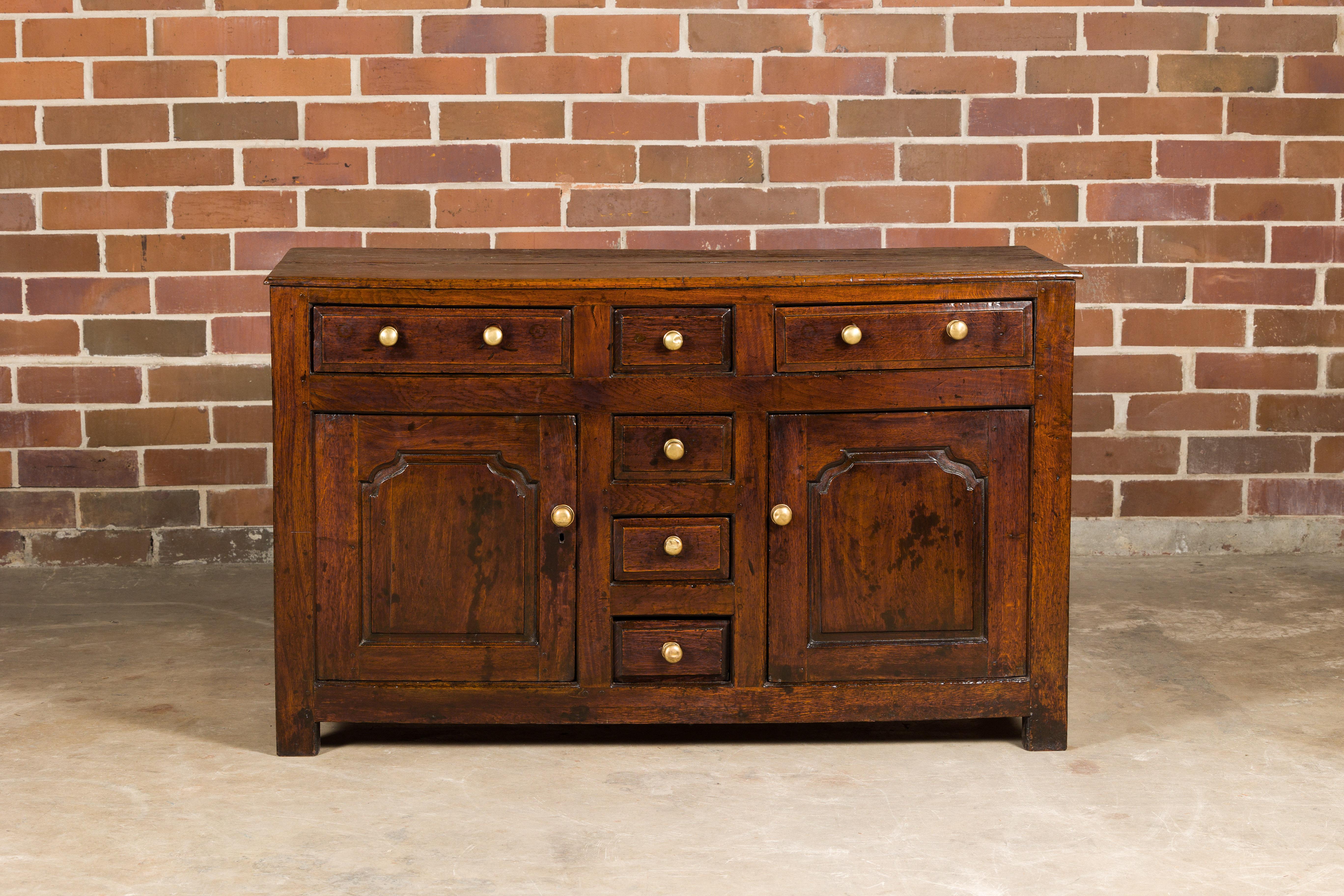 An English George III period oak buffet from circa 1800 with six drawers, two doors and nice patina. Step back into the timeless elegance of early 19th-century England with this George III period oak buffet. Originating circa 1800, its enduring