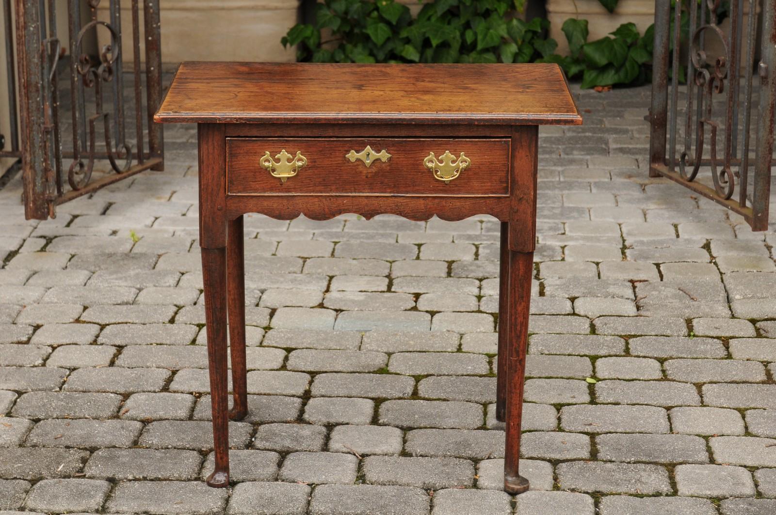 An English George III oak side table from the early 19th century, with single drawer and pad feet. Born in England during the reign of King George III, this charming side table features a rectangular top, sitting above a single drawer fitted with