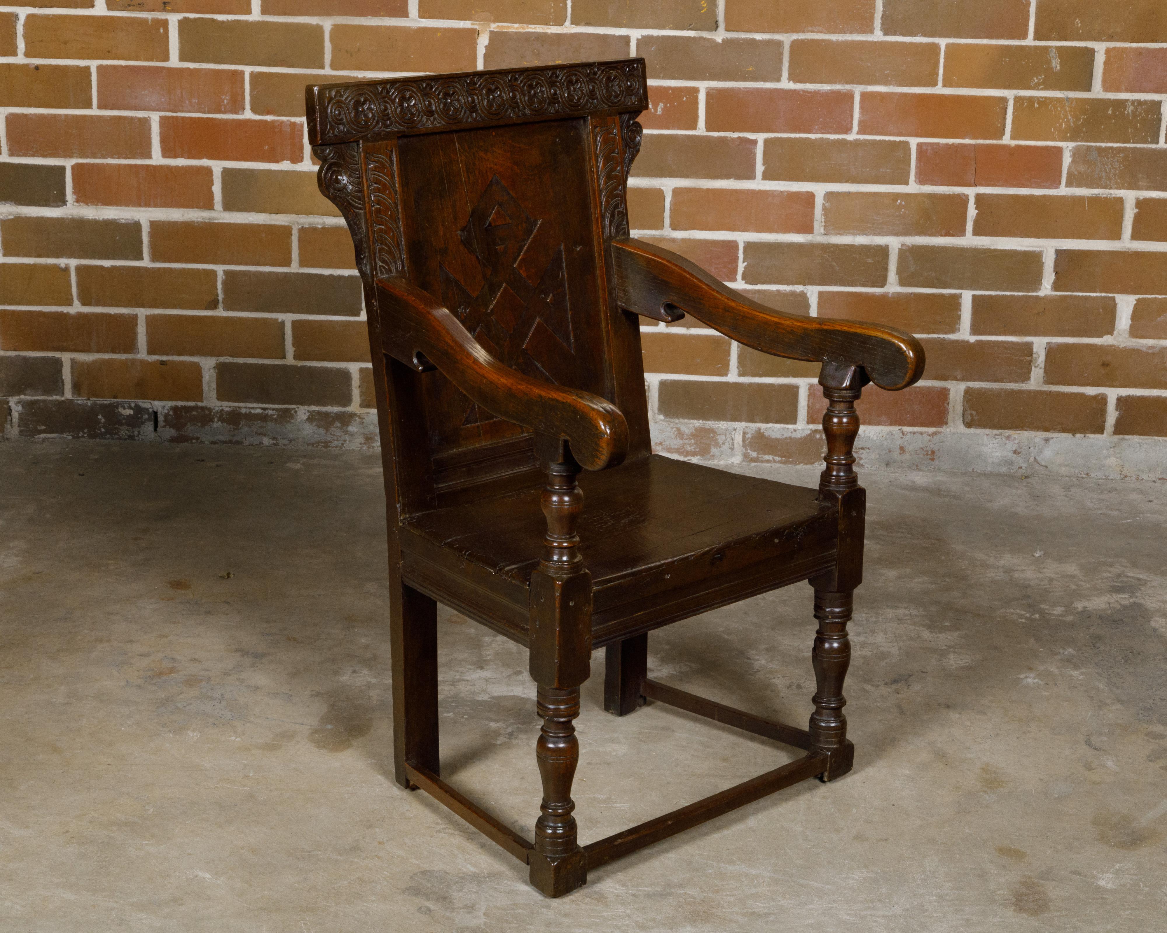 Fauteuil anglais en chêne du début du XVIIIe siècle, avec dossier sculpté, accoudoirs inclinés et pieds tournés. Cet exquis fauteuil en chêne anglais du début du XVIIIe siècle respire l'élégance intemporelle et l'artisanat de maître. Le dossier de