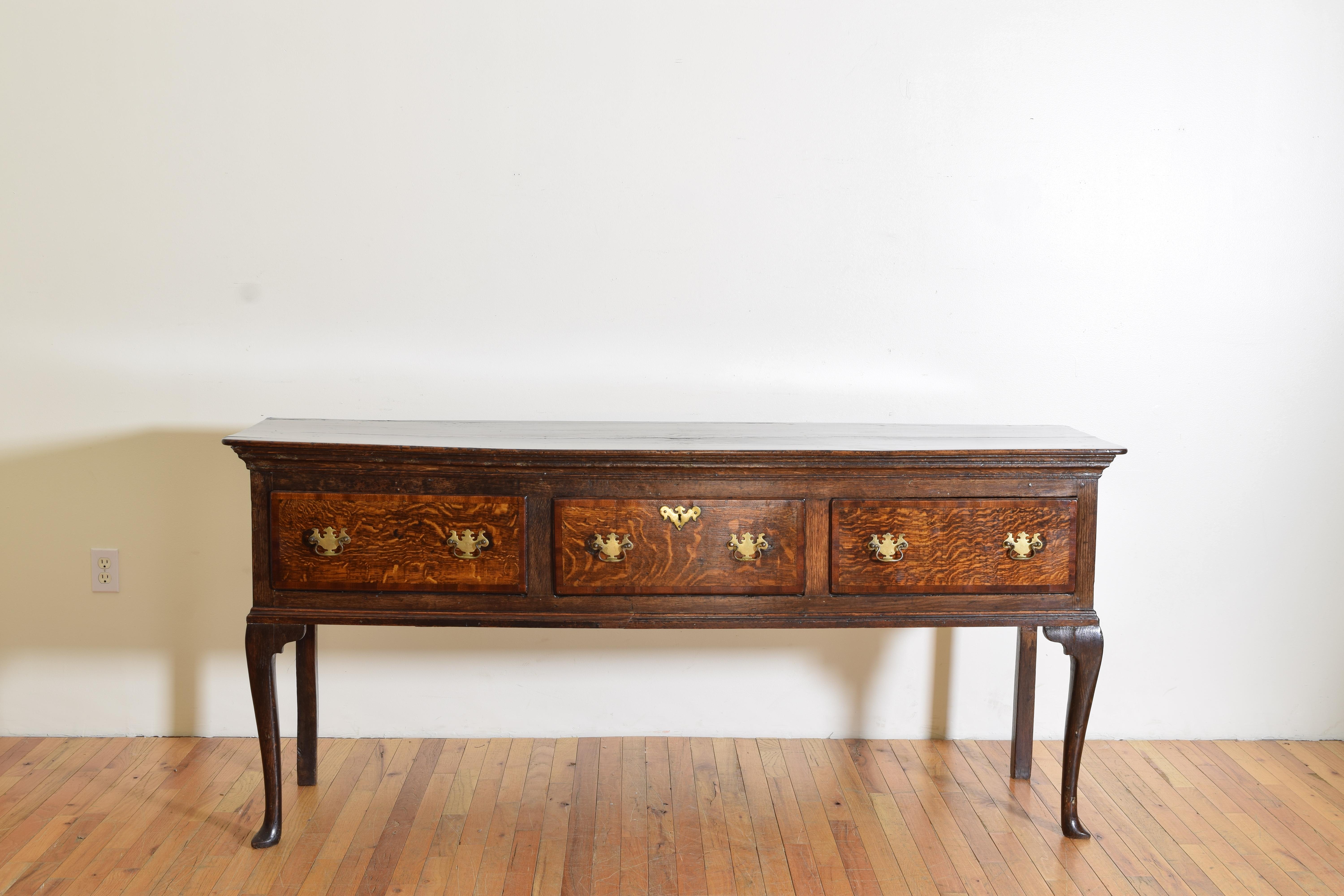 having a rectangular top with triple molded edge above a conforming case housing three drawers of beautifully figured oak, retaining antique brass backplates and handles, the case raised on tapering slightly cabriole legs terminating in spade feet