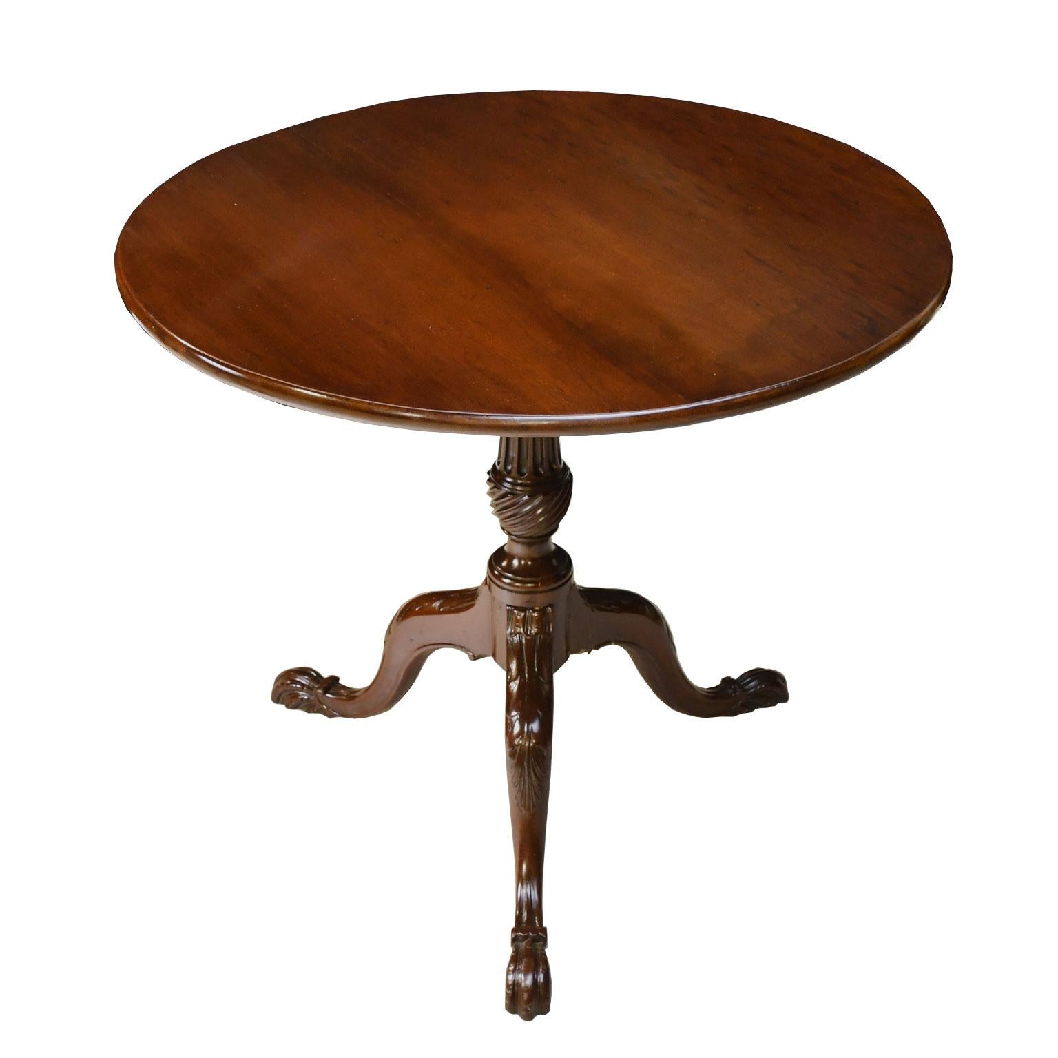 A very handsome English, George III tripod tea table in a fine, dense plum mahogany with round tilt-top over fluted, spiral-vase turned column on three out-swept cabriole legs with well-articulated acanthus carvings on the knees, and ending in