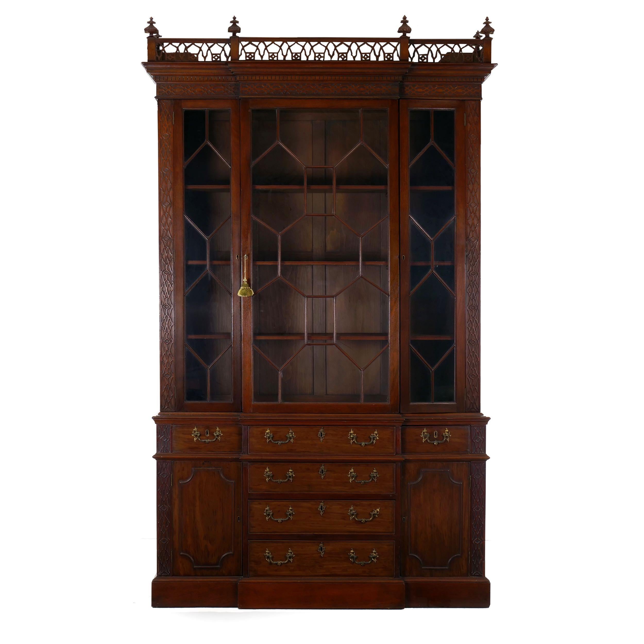 A gorgeous London revival from the last quarter of the 19th century, this Fine library bookcase cabinet is designed in the Gothic taste of the George III period a century prior. With extensive applied fretwork and angular pierced fretwork in the